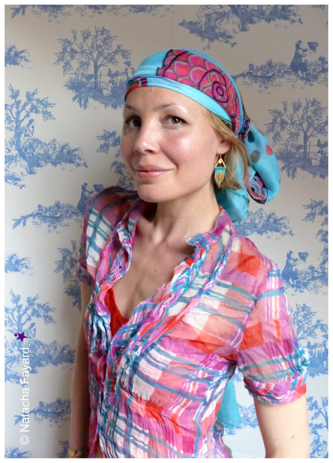 Peut inclure: Une femme portant un foulard à motifs bleus et roses et une chemise à carreaux rose, bleu et blanc. Elle porte des boucles d'oreilles turquoise.