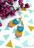 Peut inclure: Une paire de boucles d'oreilles triangulaires dorées avec une frange de perles turquoise, jaunes et roses.