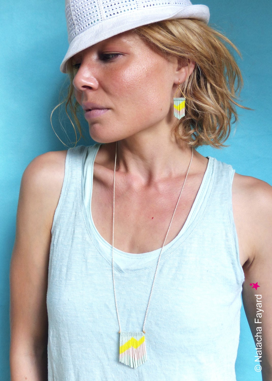 Peut inclure: Une femme portant un chapeau blanc et un débardeur bleu clair avec un collier et des boucles d'oreilles assortis en perles jaunes et roses. 