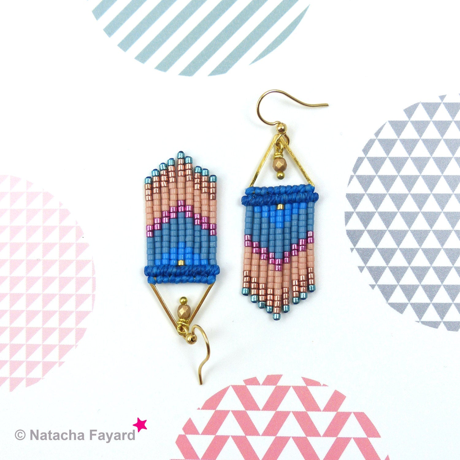 Peut inclure: Une paire de boucles d'oreilles pendantes avec un motif géométrique. Les boucles d'oreilles sont faites de perles bleues, roses et dorées et ont un cadre en fil doré.