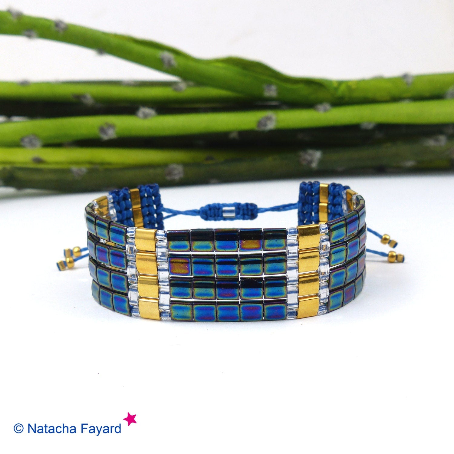 Peut inclure: Un bracelet multi-rangs avec des perles irisées bleues et dorées. Le bracelet est doté d'une fermeture à nœud coulissant.