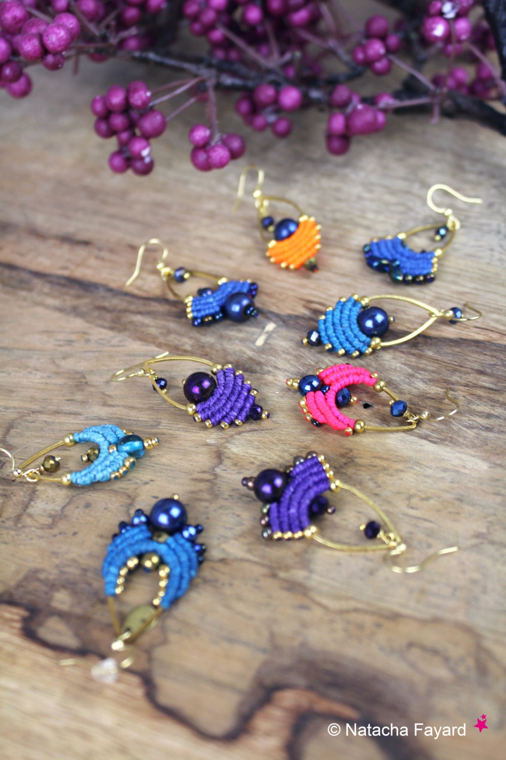 Peut inclure: Un ensemble de huit boucles d'oreilles faites à la main de couleurs vives, comprenant du bleu, du violet, du rose et de l'orange. Chaque boucle d'oreille présente un design unique avec une perle bleu foncé au centre.