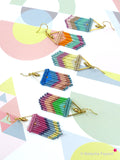 Peut inclure: Cinq paires de boucles d'oreilles en perles colorées avec des accents triangulaires dorés. Chaque paire présente une combinaison de couleurs de perles différente, notamment le rose, le bleu, le vert, l'orange et le marron.