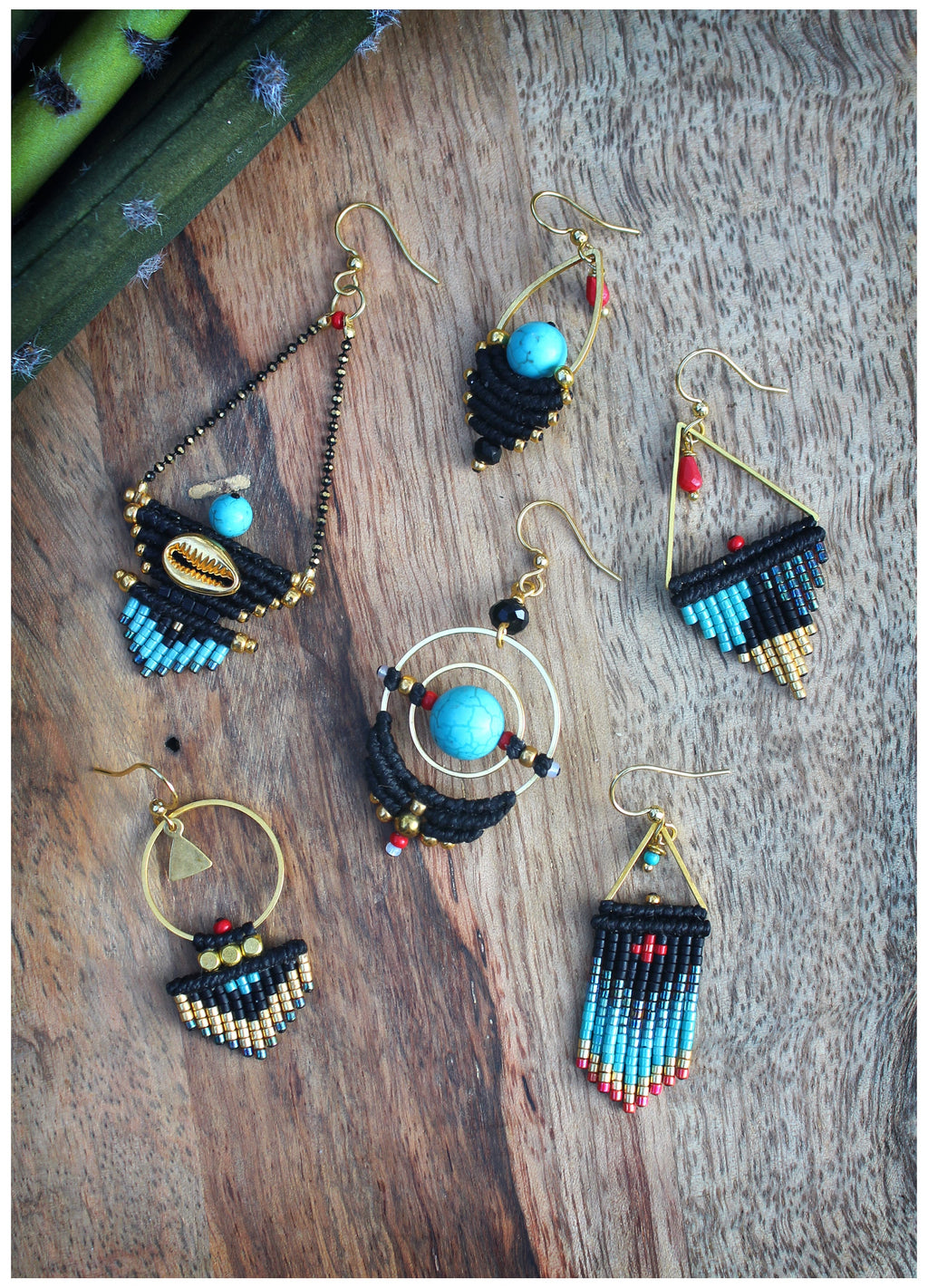 Peut inclure: Cinq paires de boucles d'oreilles faites à la main avec des accents noirs et dorés. Chaque paire présente un design différent avec des perles turquoise et rouges.