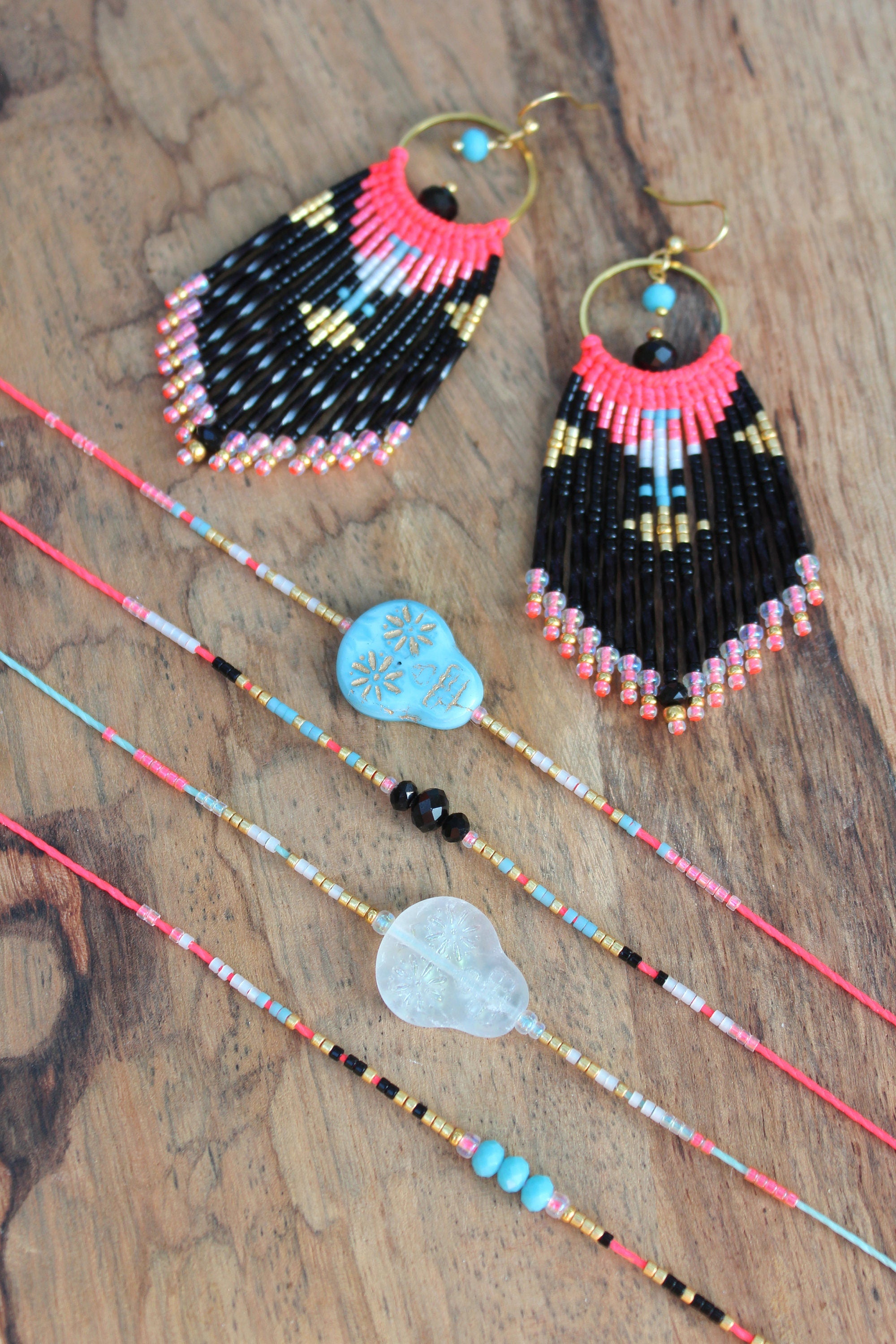 Peut inclure: Un ensemble de bijoux en perles composé de perles noires, blanches, roses et turquoise. L'ensemble comprend une paire de longues boucles d'oreilles, un collier avec un pendentif en forme de crâne turquoise et trois colliers plus courts avec un pendentif en cristal transparent.