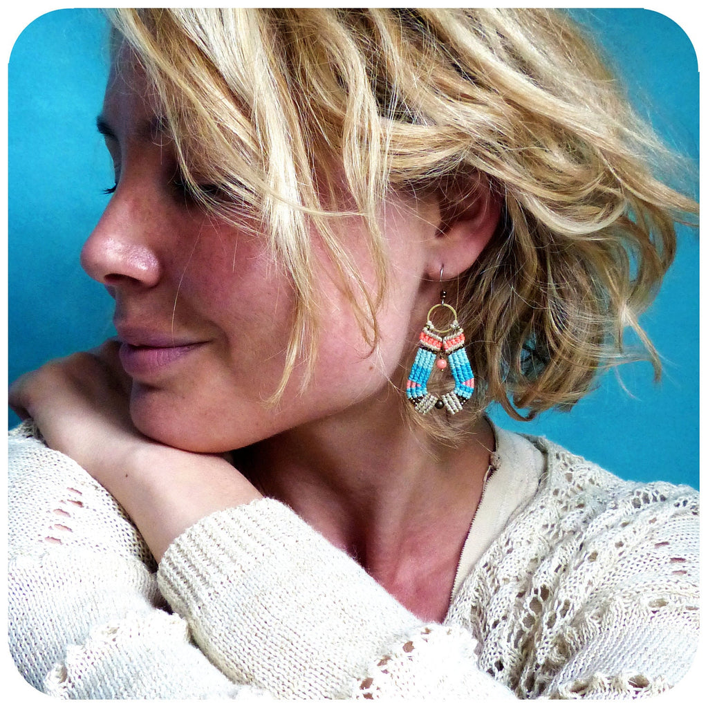 Peut inclure: Une femme aux cheveux blonds portant un pull blanc et une paire de boucles d'oreilles en perles bleues, roses et blanches.