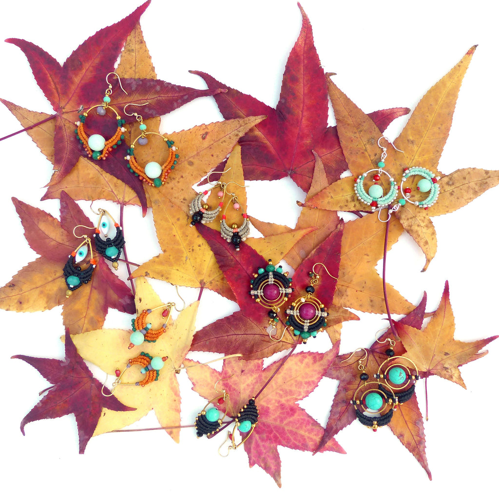 Peut inclure: Une collection de boucles d'oreilles en perles colorées avec différentes formes et motifs, disposées sur un lit de feuilles d'automne.
