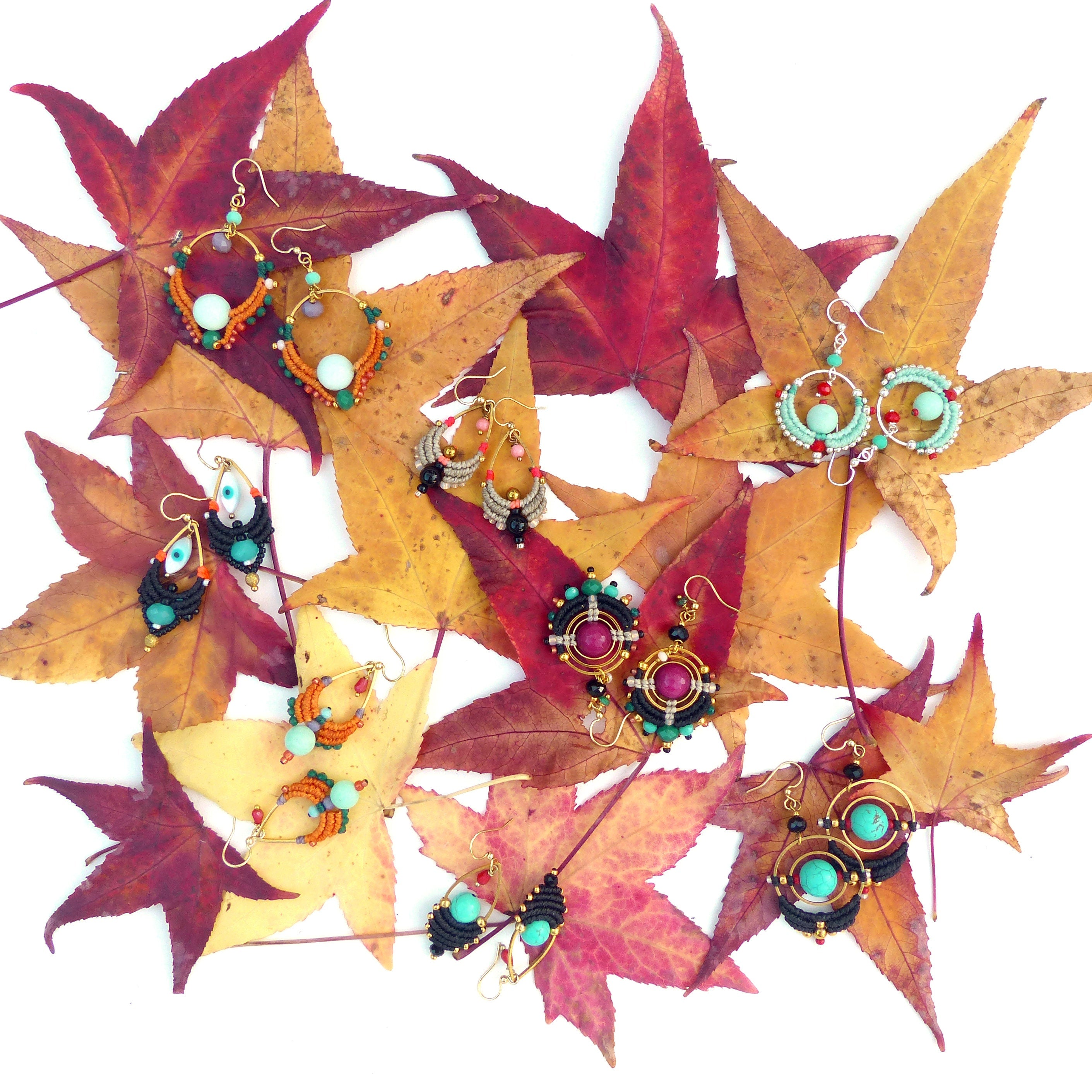 Peut inclure: Une collection de boucles d'oreilles en perles colorées avec différentes formes et motifs, disposées sur un lit de feuilles d'automne.