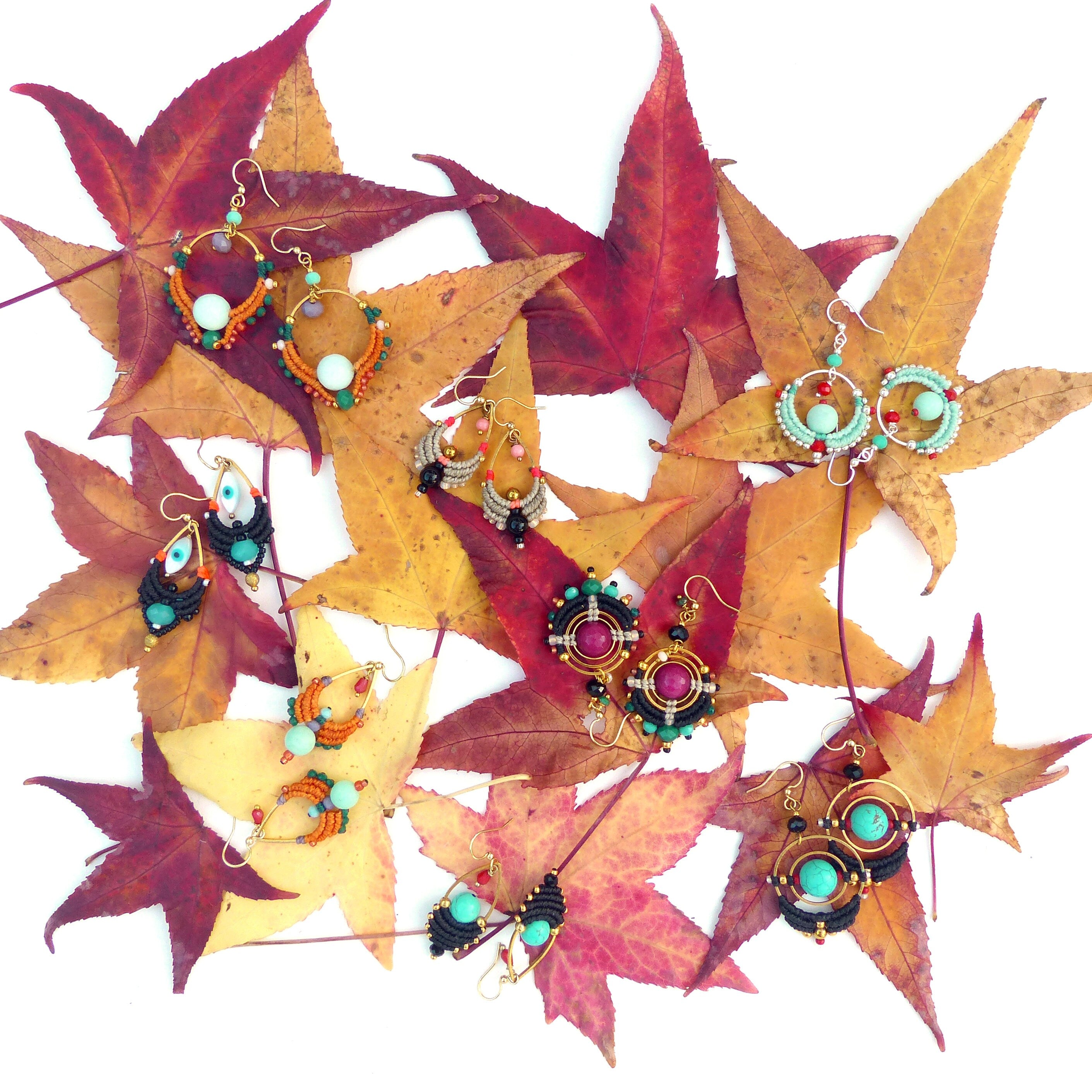 Peut inclure: Une collection de boucles d'oreilles en perles colorées avec différentes formes et motifs, disposées sur un lit de feuilles d'automne.