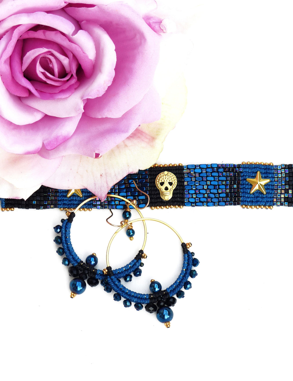 Peut inclure: Une paire de boucles d'oreilles créoles en perles bleues et noires avec des cercles dorés. Les boucles d'oreilles présentent un charme de crâne et un charme d'étoile.