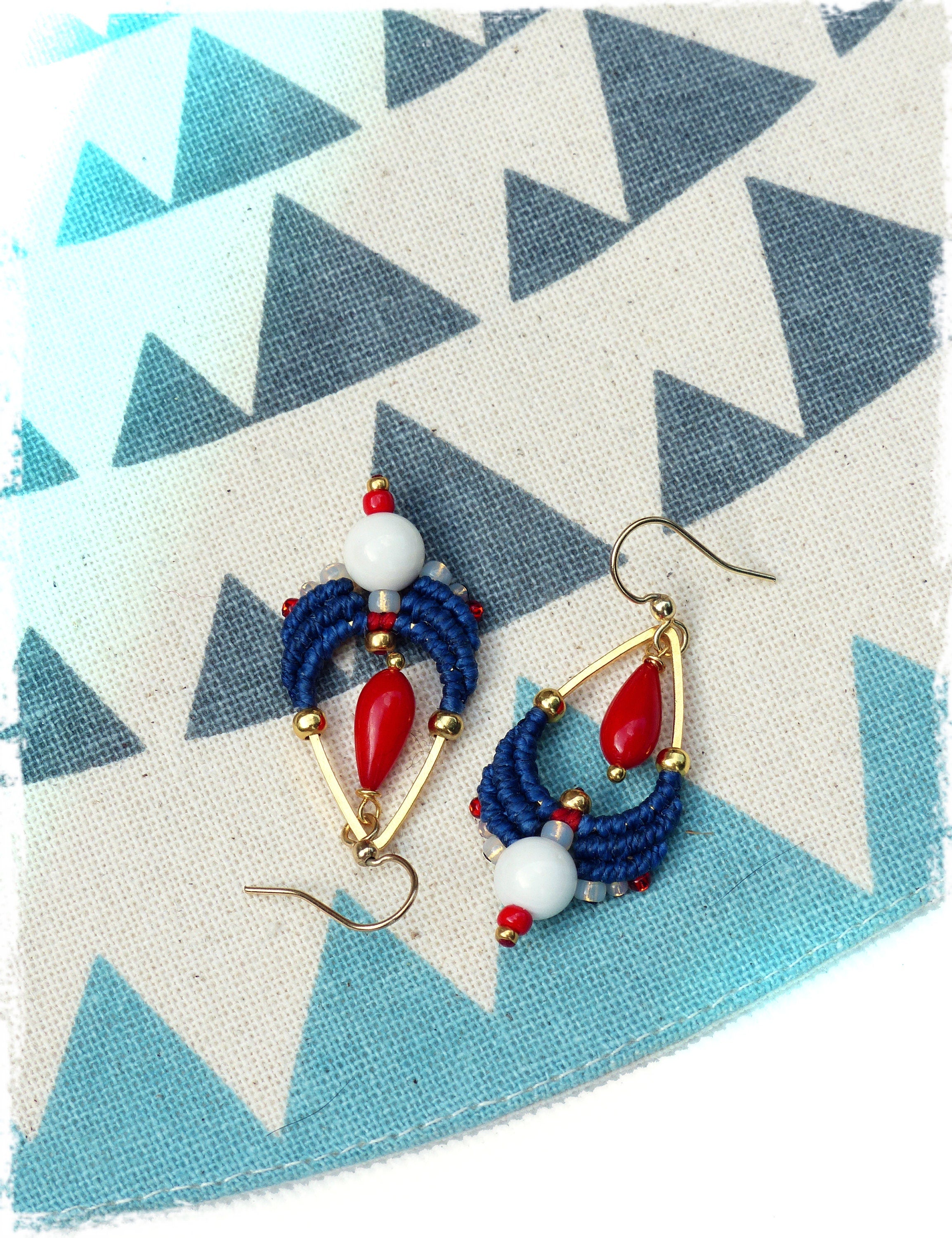 Peut inclure: Une paire de boucles d'oreilles en perles bleues et rouges avec des accents dorés. Les boucles d'oreilles ont la forme d'une larme et comportent une perle blanche au centre.