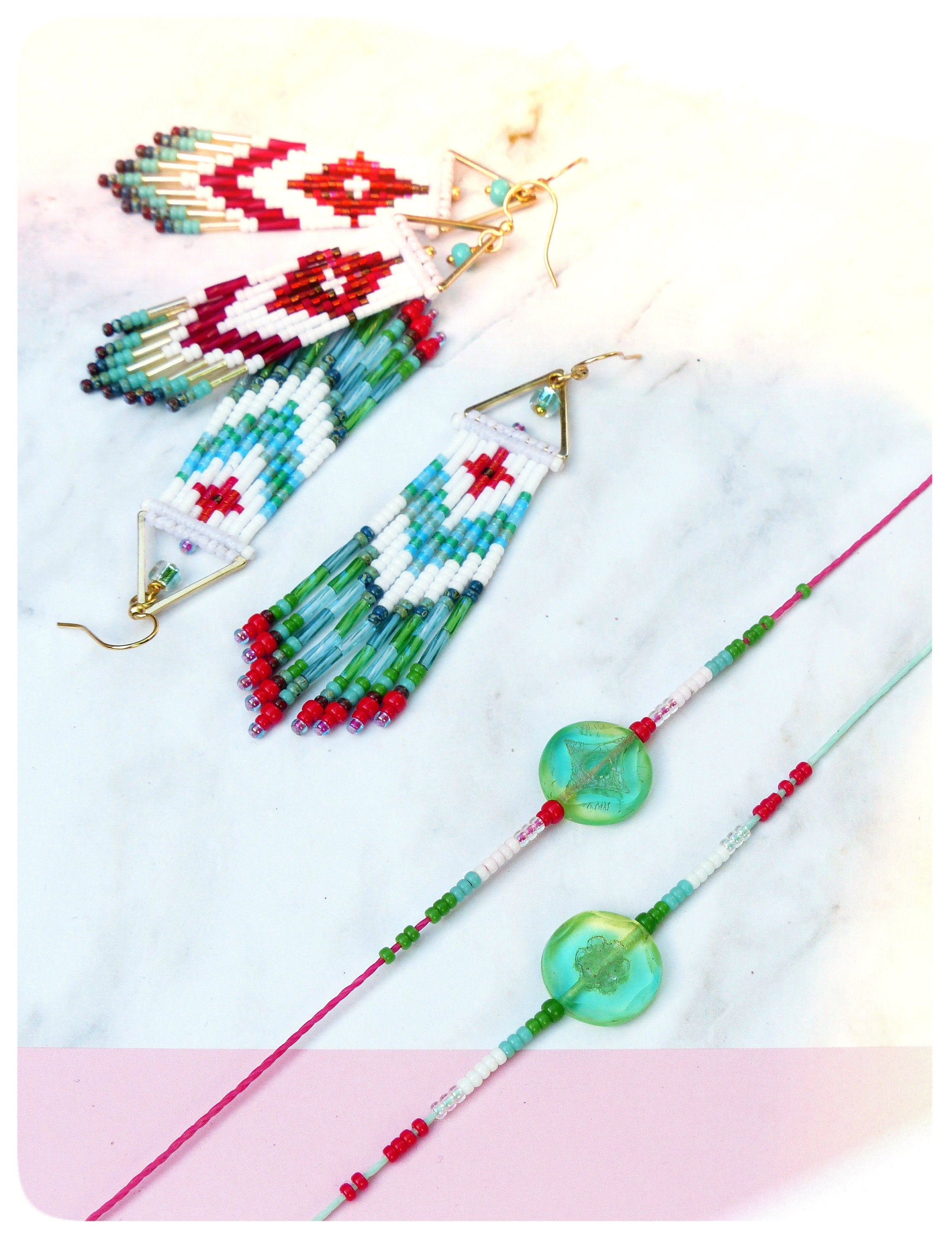Peut inclure: Une paire de boucles d'oreilles en perles avec un motif géométrique en rouge, blanc et bleu. Les boucles d'oreilles sont suspendues à des crochets dorés. Il y a aussi deux bracelets en perles avec des perles vertes et blanches et une grosse perle verte au centre.