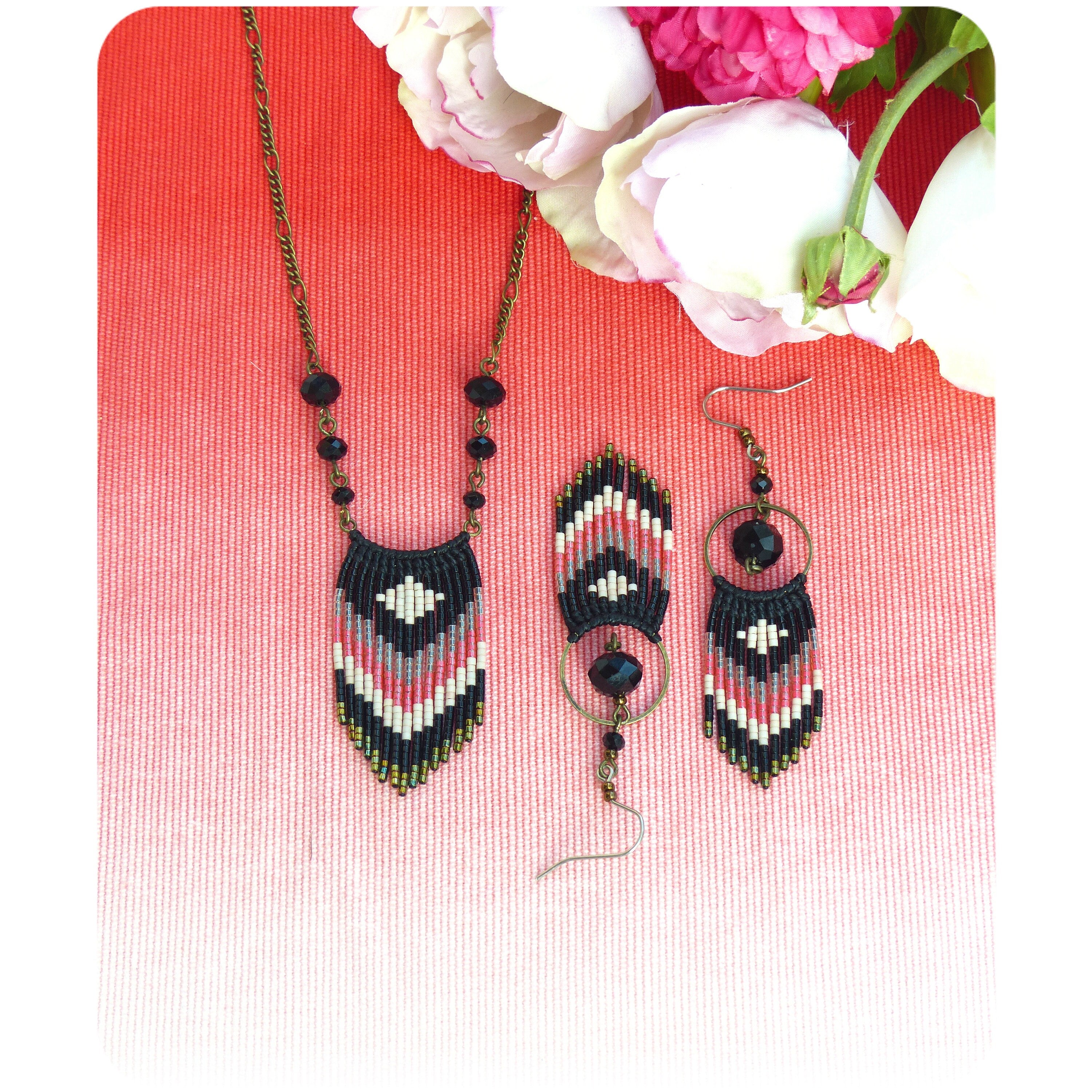Peut inclure: Un ensemble de bijoux en perles noires, blanches et roses avec un motif géométrique. L'ensemble comprend un collier et une paire de boucles d'oreilles.