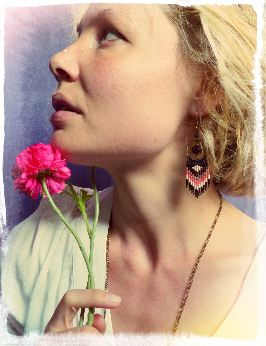 Peut inclure: Une femme aux cheveux blonds portant un collier en or et des boucles d'oreilles en perles. Elle tient une fleur rose dans sa main.