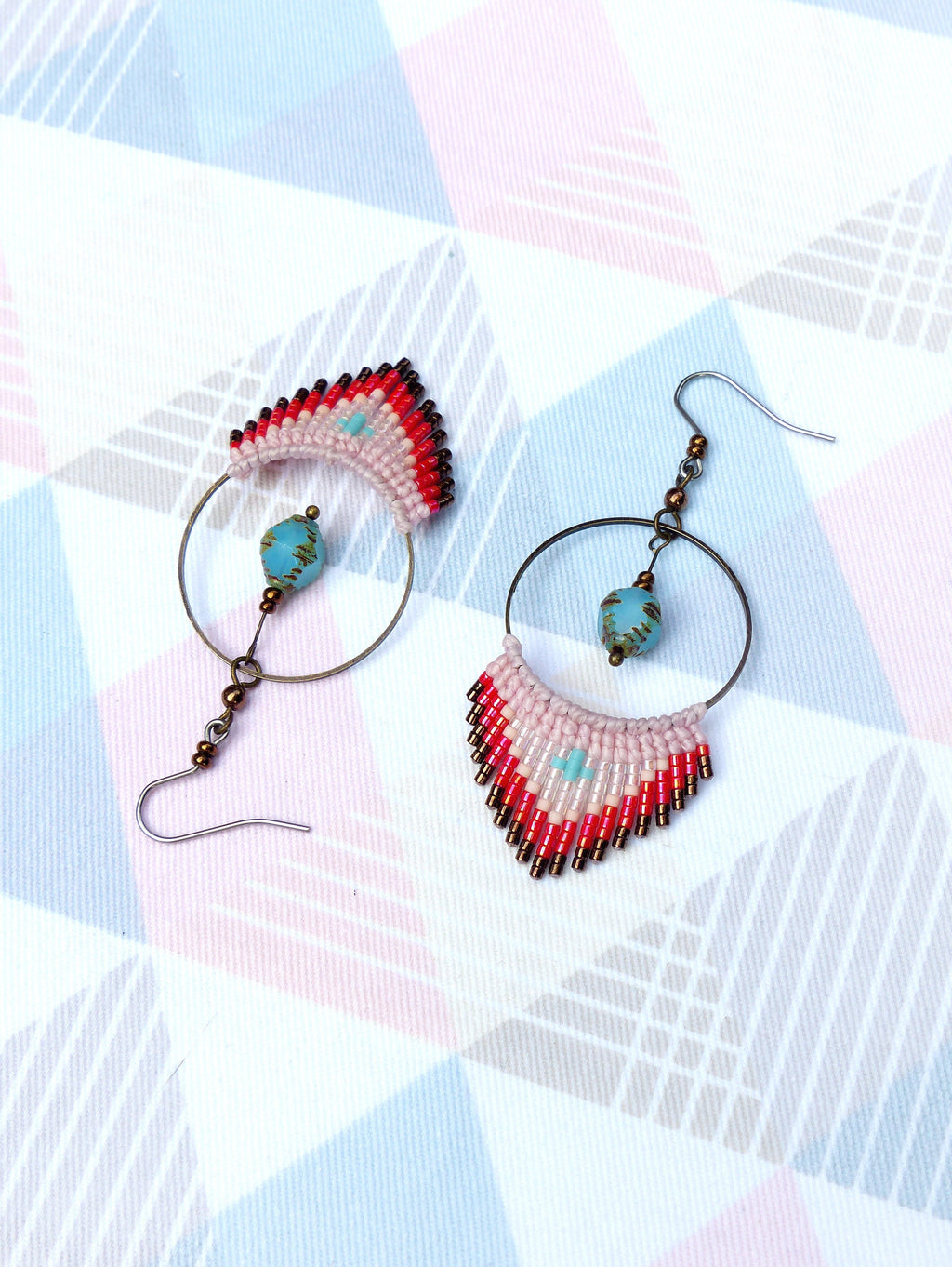 Peut inclure: Une paire de boucles d'oreilles créoles avec une frange de perles. La frange est composée de perles blanches, roses, rouges et brunes. Les créoles sont argentées et ont une perle turquoise qui pend.