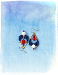 Peut inclure: Une paire de boucles d'oreilles pendantes avec des perles bleues, rouges et blanches. Les boucles d'oreilles ont une finition dorée et sont suspendues à un crochet doré.