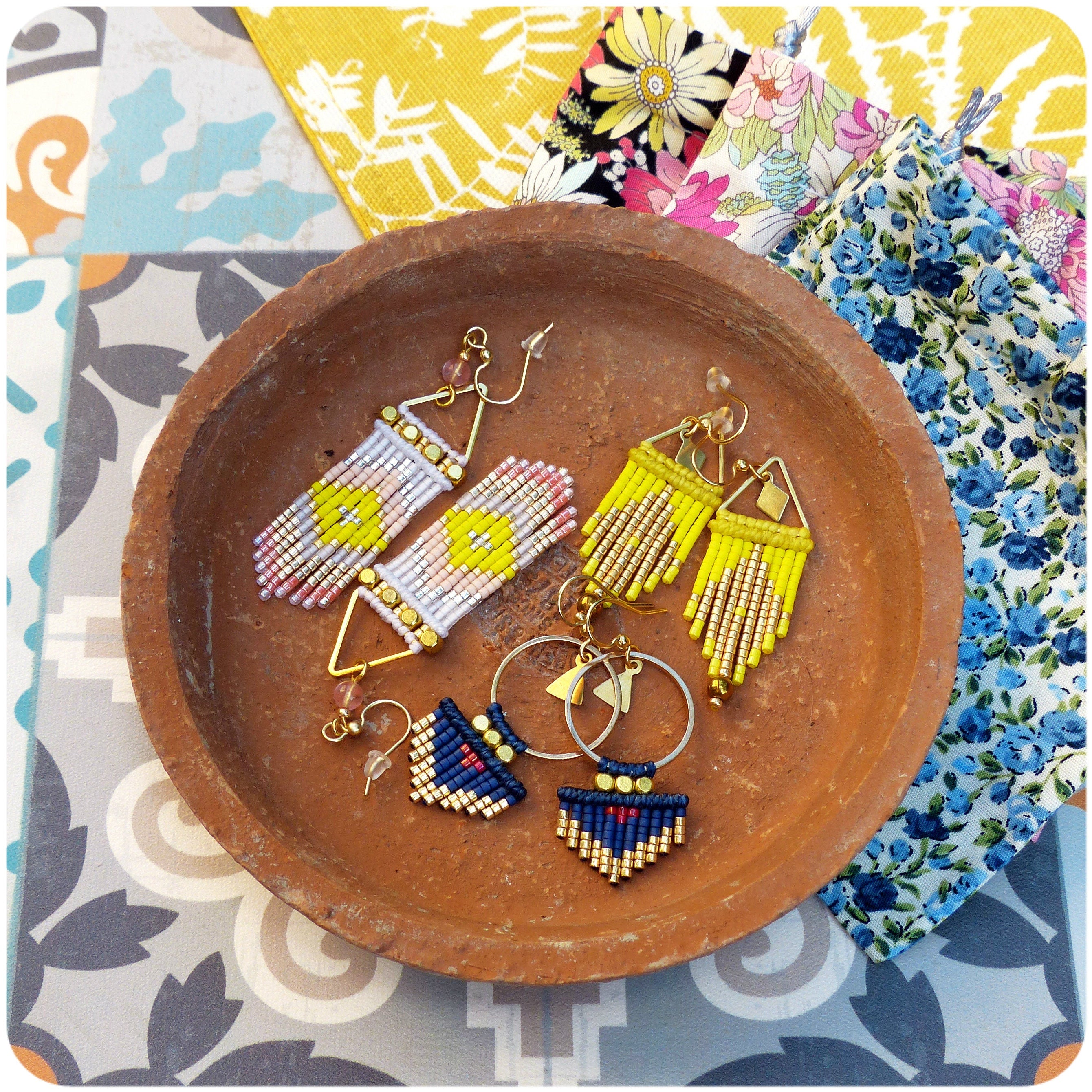 Peut inclure: Gros plan sur trois paires de boucles d'oreilles en perles. Les boucles d'oreilles sont faites de petites perles colorées et ont des styles variés. Les boucles d'oreilles sont présentées sur une assiette en terre cuite brune.