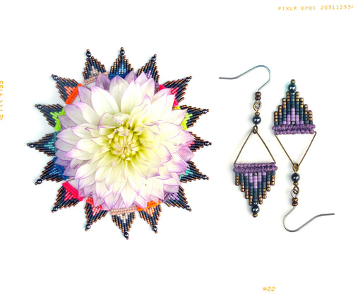 Peut inclure: Une paire de boucles d'oreilles en perles violettes et noires avec un motif géométrique. Les boucles d'oreilles sont suspendues à un crochet argenté. Les boucles d'oreilles sont présentées sur un fond blanc avec une fleur en arrière-plan.