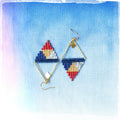 Peut inclure: Une paire de boucles d'oreilles triangulaires géométriques avec des accents rouge, blanc, bleu et or. Les boucles d'oreilles sont faites de petites perles et ont un cadre en fil d'or.