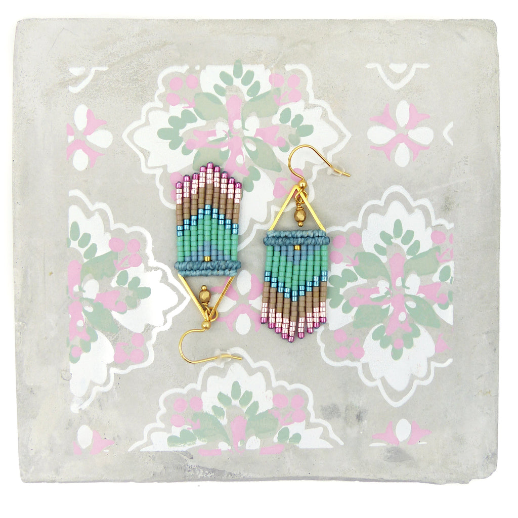 Peut inclure: Une paire de boucles d'oreilles pendantes dorées avec un motif géométrique. Les boucles d'oreilles sont faites de petites perles dans des tons de rose, bleu, vert et marron.