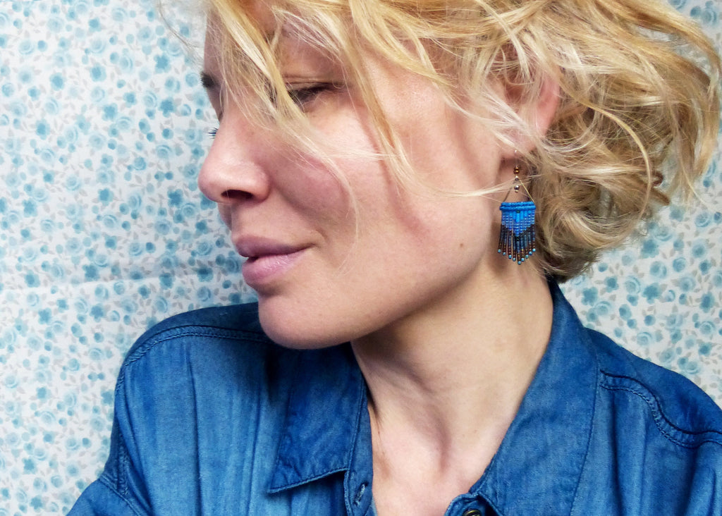Peut inclure: Une femme aux cheveux blonds portant une chemise en jean bleue et des boucles d'oreilles en perles bleues et brunes.