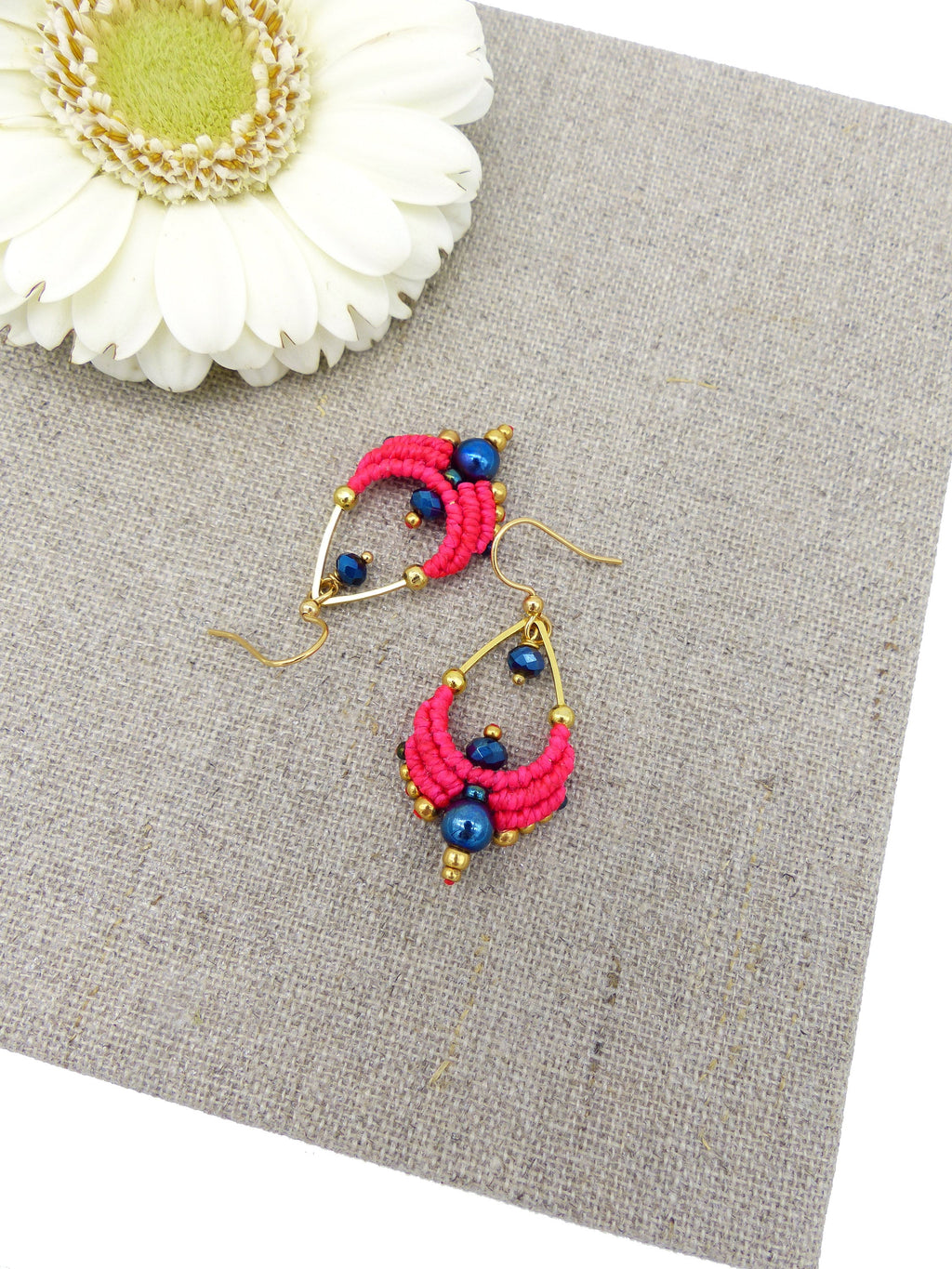 Peut inclure: Une paire de boucles d'oreilles rose et bleu avec des accents dorés. Les boucles d'oreilles sont faites de petites perles et ont une forme de larme.