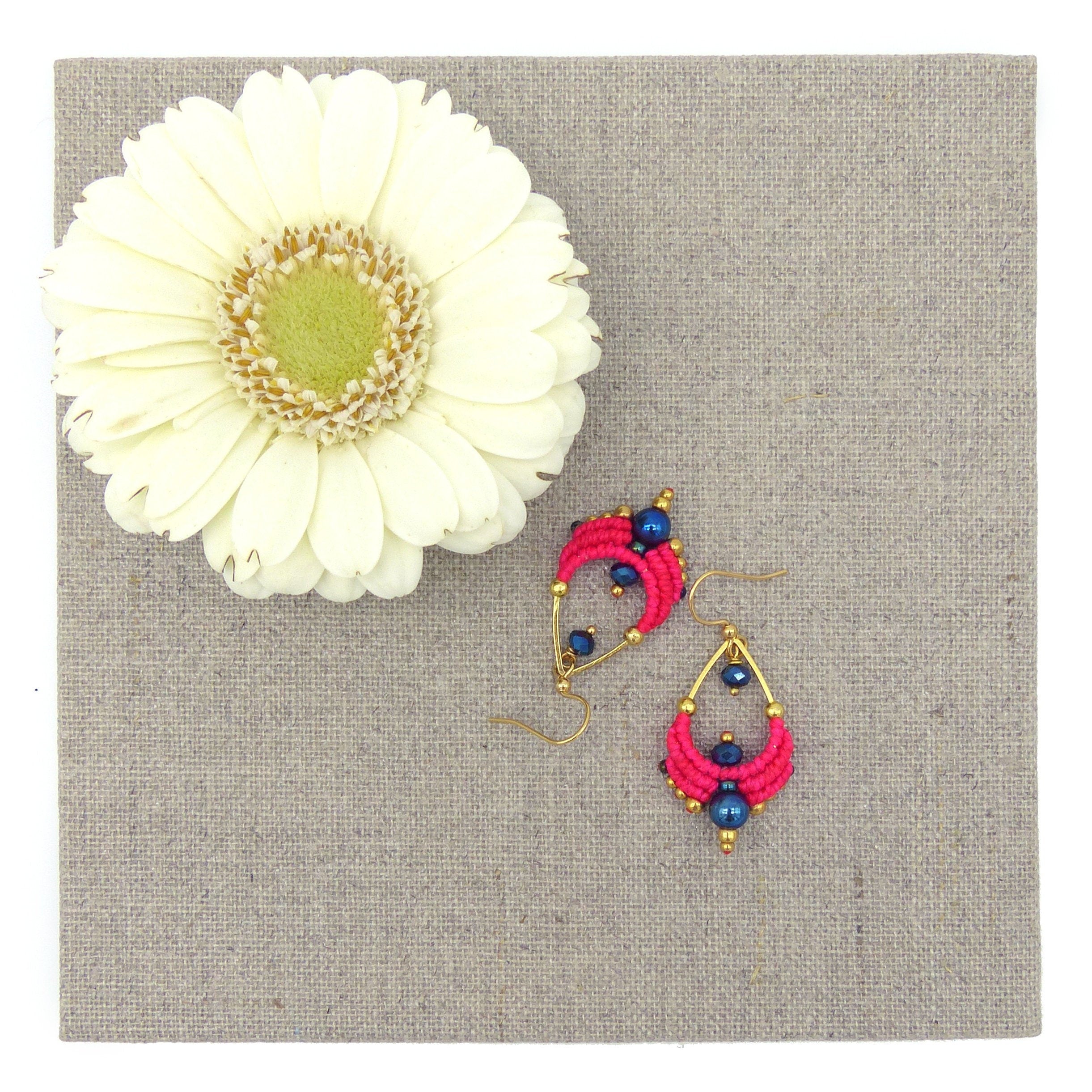 Peut inclure: Une paire de boucles d'oreilles pendantes en forme de goutte d'eau, composées de perles roses et bleues avec des accents dorés.