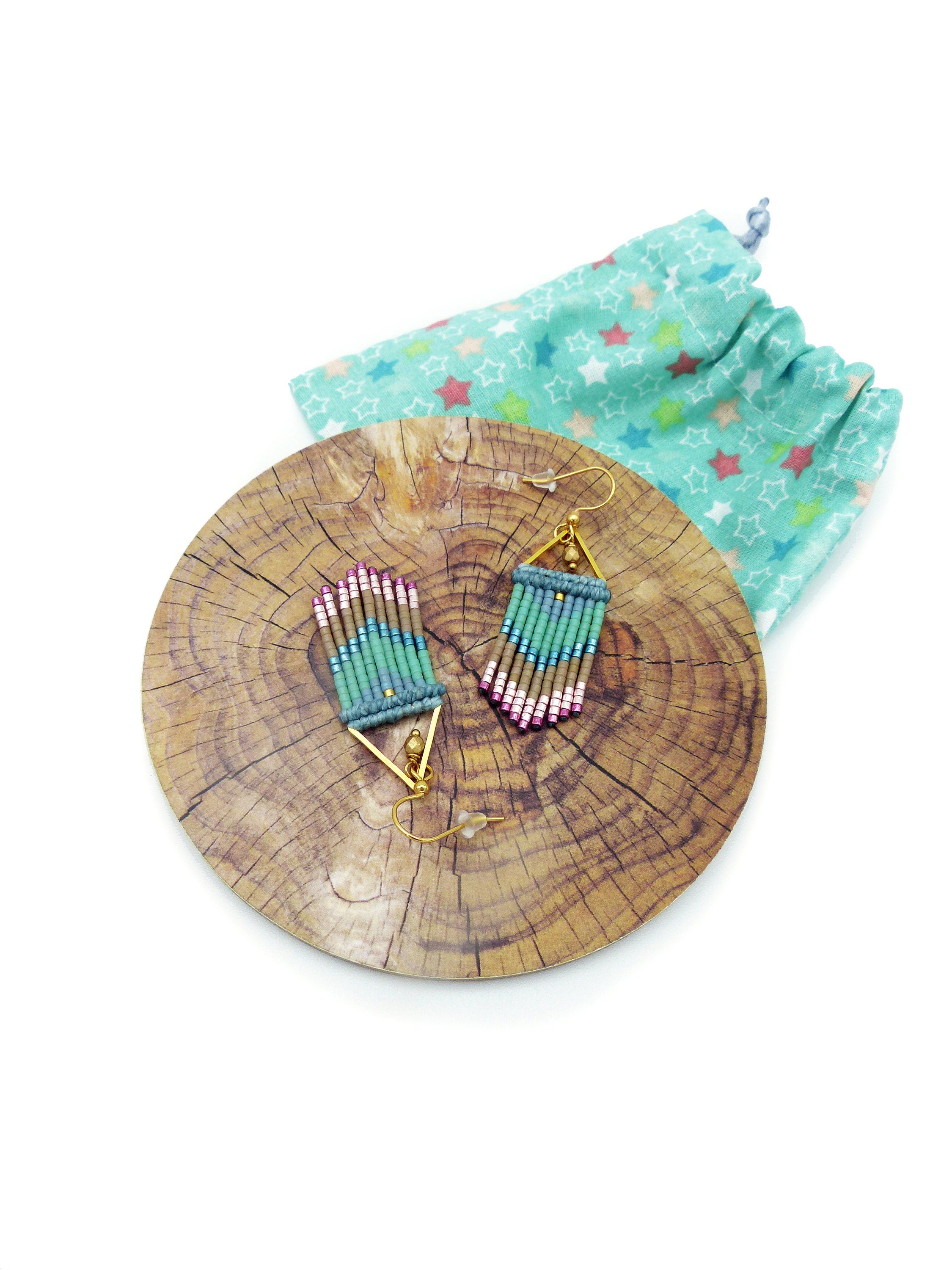 Peut inclure: Une paire de boucles d'oreilles pendantes faites à la main avec un design géométrique. Les boucles d'oreilles sont faites de perles turquoise, vertes et roses et ont des crochets dorés.