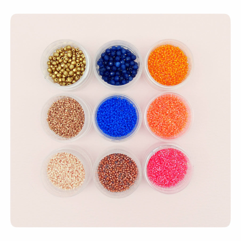 Peut inclure: Dix petits contenants remplis de perles de rocaille colorées. Les perles sont de différentes couleurs, notamment or, bleu, orange, marron et rose.