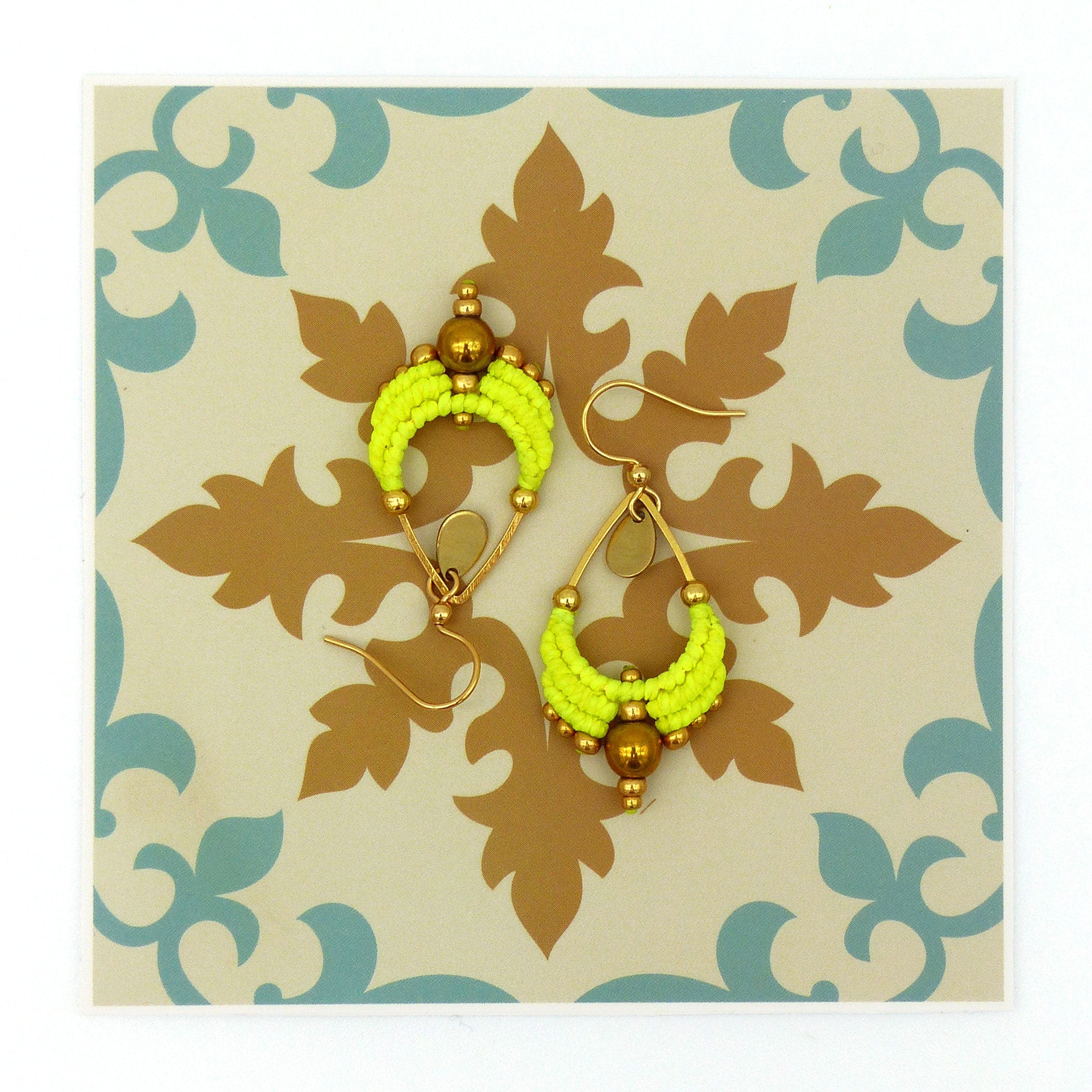 Peut inclure: Une paire de boucles d'oreilles en perles jaunes avec des accents dorés. Les boucles d'oreilles ont la forme d'une larme et sont ornées d'une petite perle dorée au bas.