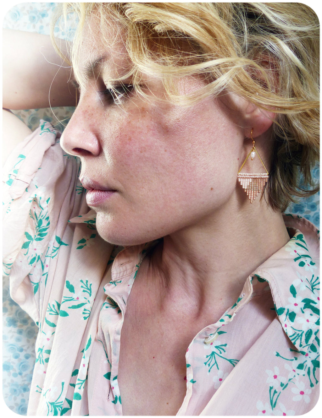 Peut inclure: Une femme aux cheveux blonds portant une chemise rose à fleurs avec une boucle d'oreille triangulaire en perles dorées et roses.