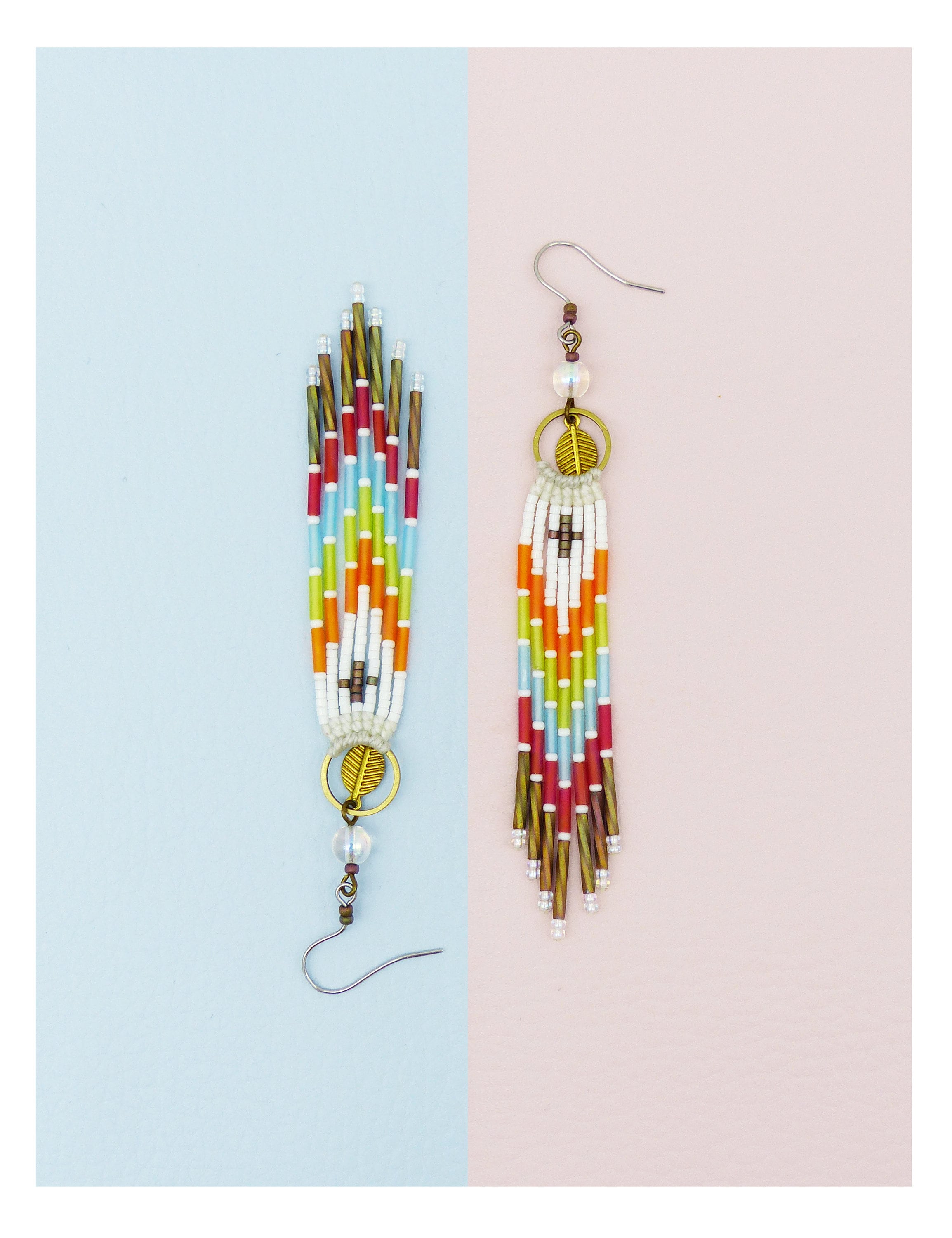 Peut inclure: Une paire de longues boucles d'oreilles en perles colorées avec un charme en feuille d'or et une perle de cristal transparente. Les boucles d'oreilles sont sur un fond bleu clair et rose.