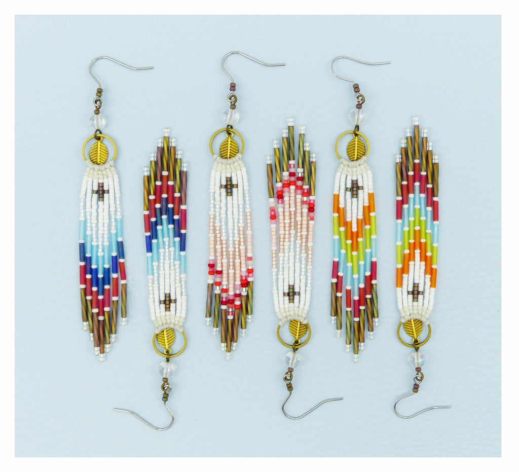 Peut inclure: Cinq paires de longues boucles d'oreilles en perles avec un motif géométrique. Les boucles d'oreilles sont faites de perles blanches, rouges, bleues, vertes et orange. Chaque boucle d'oreille a un crochet doré et un petit charme en forme de feuille dorée.