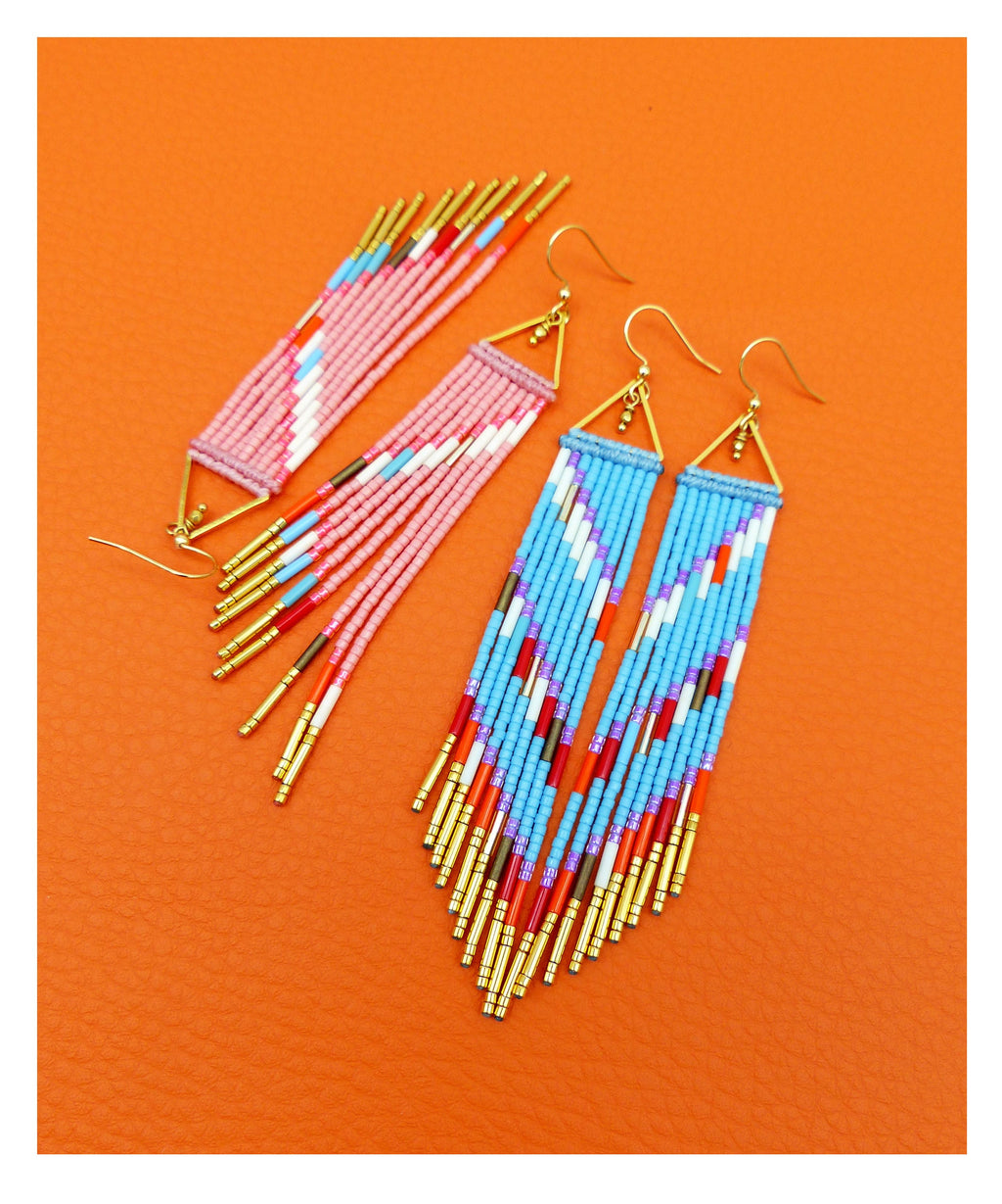 Peut inclure: Une paire de longues boucles d'oreilles en perles avec des motifs géométriques. Les boucles d'oreilles sont faites de perles roses, bleues, blanches, rouges et dorées. Les boucles d'oreilles sont suspendues à des crochets dorés.