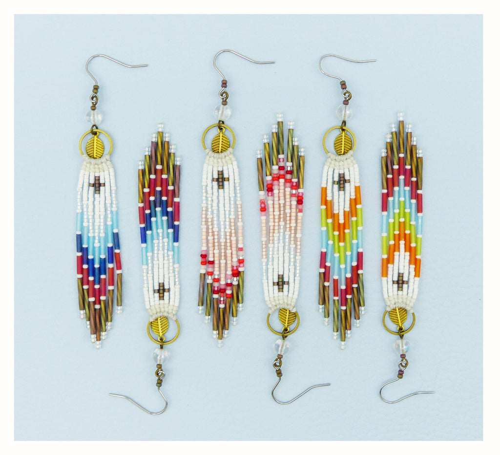 Peut inclure: Six boucles d'oreilles pendantes en perles. Chaque boucle d'oreille présente une base blanche avec des accents colorés dans les tons de bleu, rouge, rose, vert et orange. Les boucles d'oreilles ont des détails de feuilles et de cerceaux dorés et des perles transparentes.