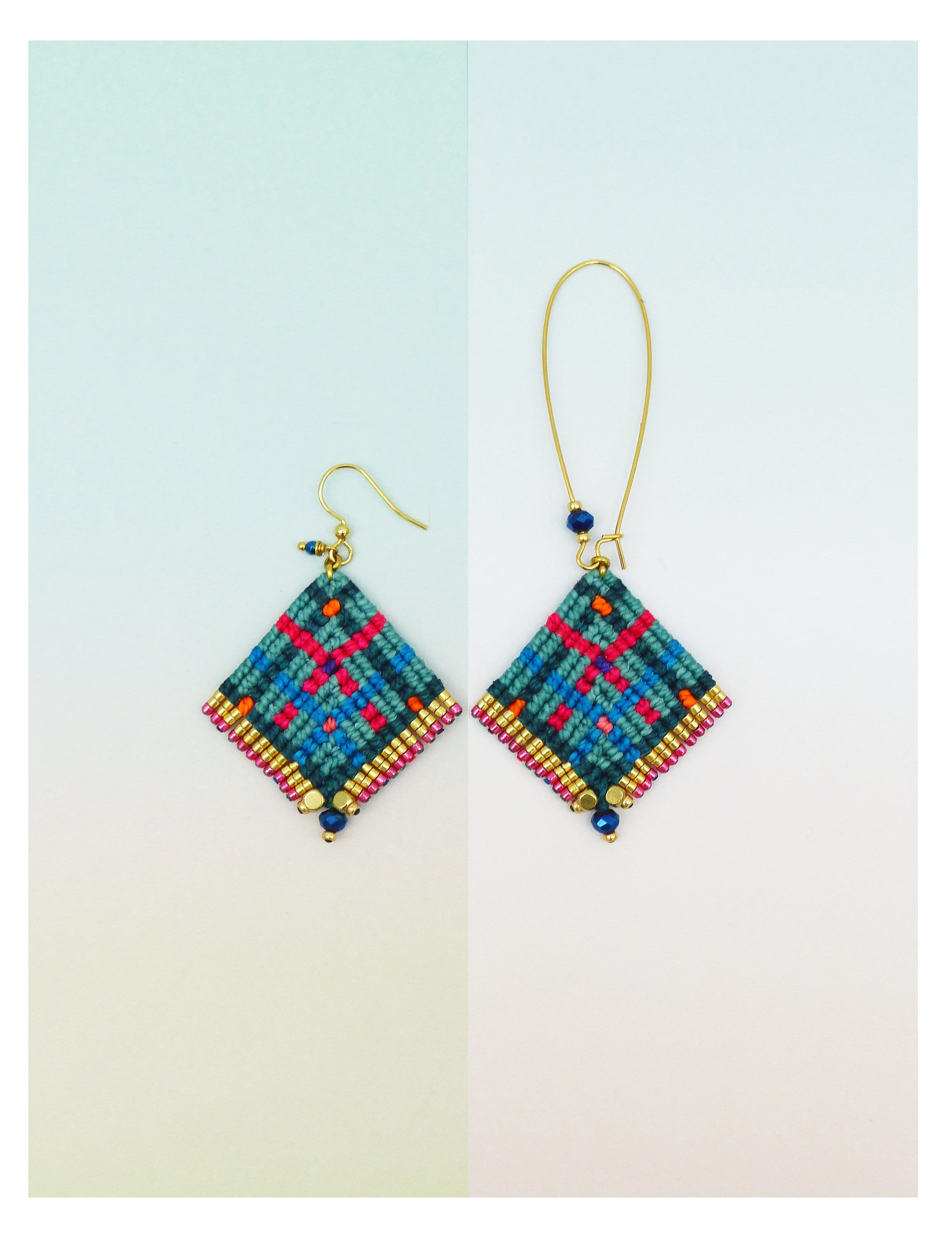 Peut inclure: Deux boucles d'oreilles macramé faites à la main. Chaque boucle d'oreille présente une forme de losange avec un motif à carreaux bleu sarcelle, rouge et orange. Les bords sont bordés de perles dorées et les boucles d'oreilles ont des crochets d'oreilles dorés et des perles bleues.
