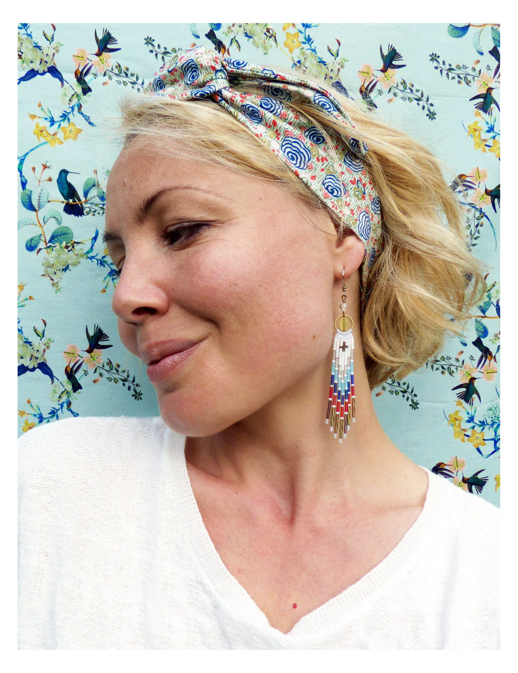 Peut inclure: Une femme portant une chemise blanche et un bandeau à motifs avec un nœud noué. Elle porte de longues boucles d'oreilles en perles avec un accent doré.