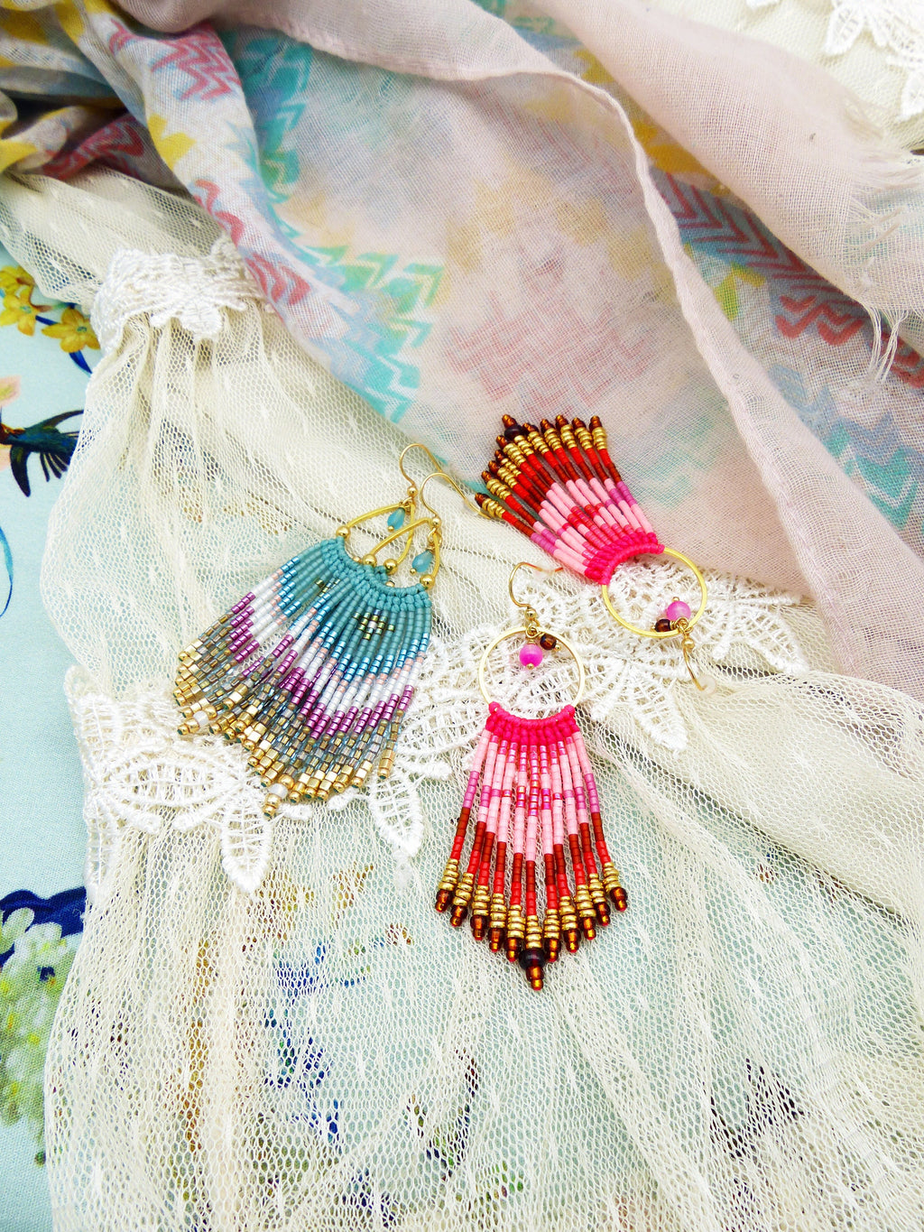 Peut inclure: Une paire de boucles d'oreilles en perles avec des accents dorés. Une boucle d'oreille est bleue, rose et blanche, et l'autre est rouge, rose et blanche.