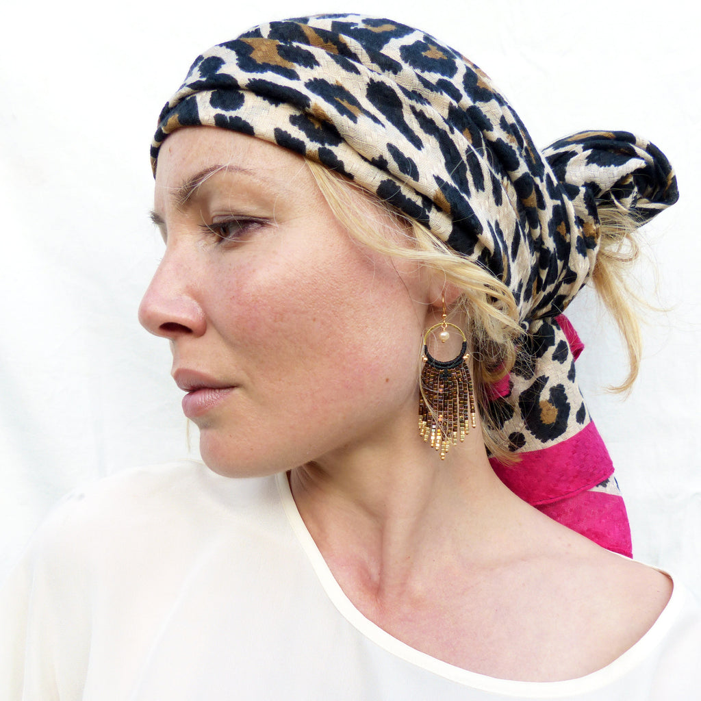 Peut inclure: Une femme portant un foulard à imprimé léopard et de longues boucles d'oreilles dorées à perles. Les boucles d'oreilles sont pendantes et ont un design circulaire.