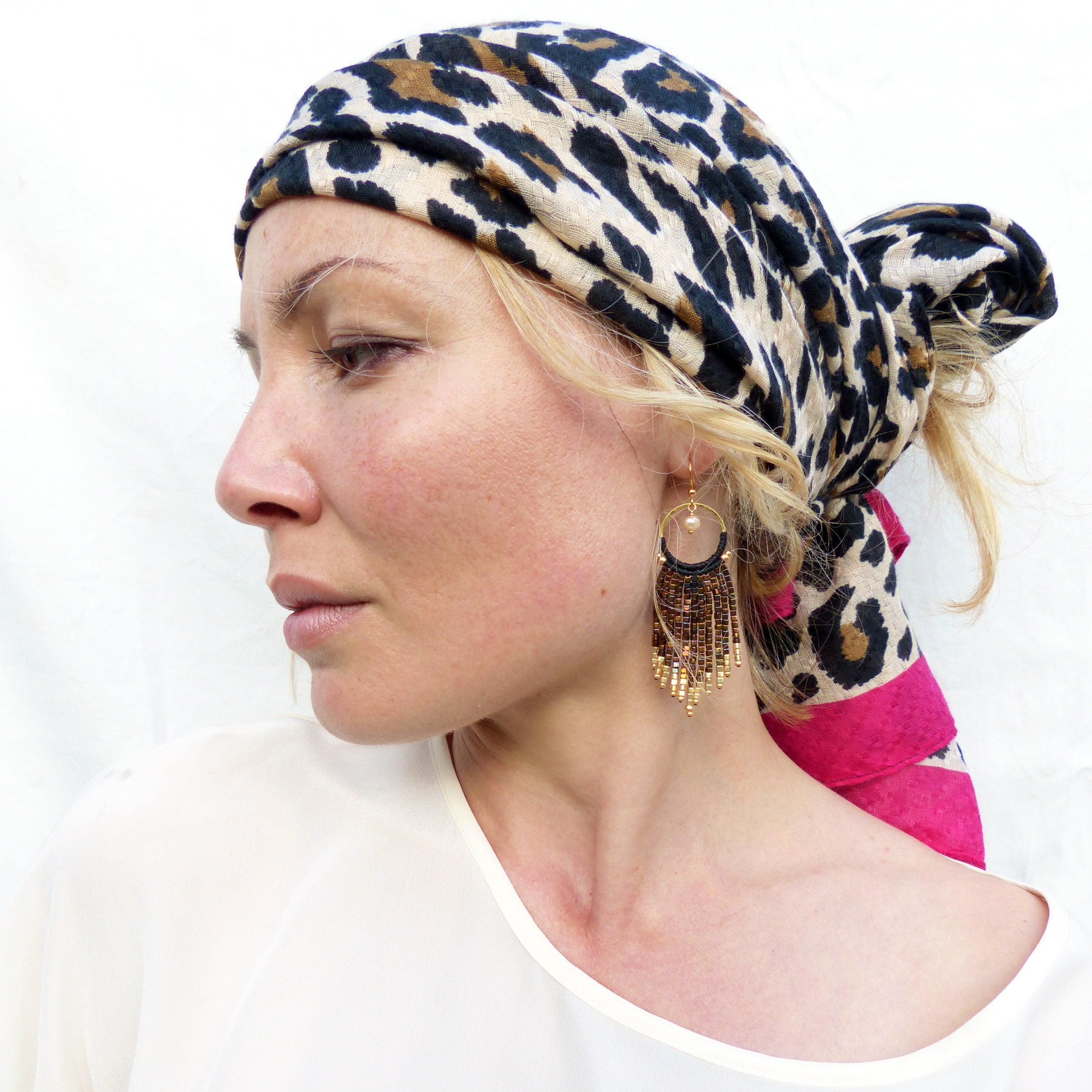 Peut inclure: Une femme portant un foulard à imprimé léopard et de longues boucles d'oreilles dorées à perles. Les boucles d'oreilles sont pendantes et ont un design circulaire.