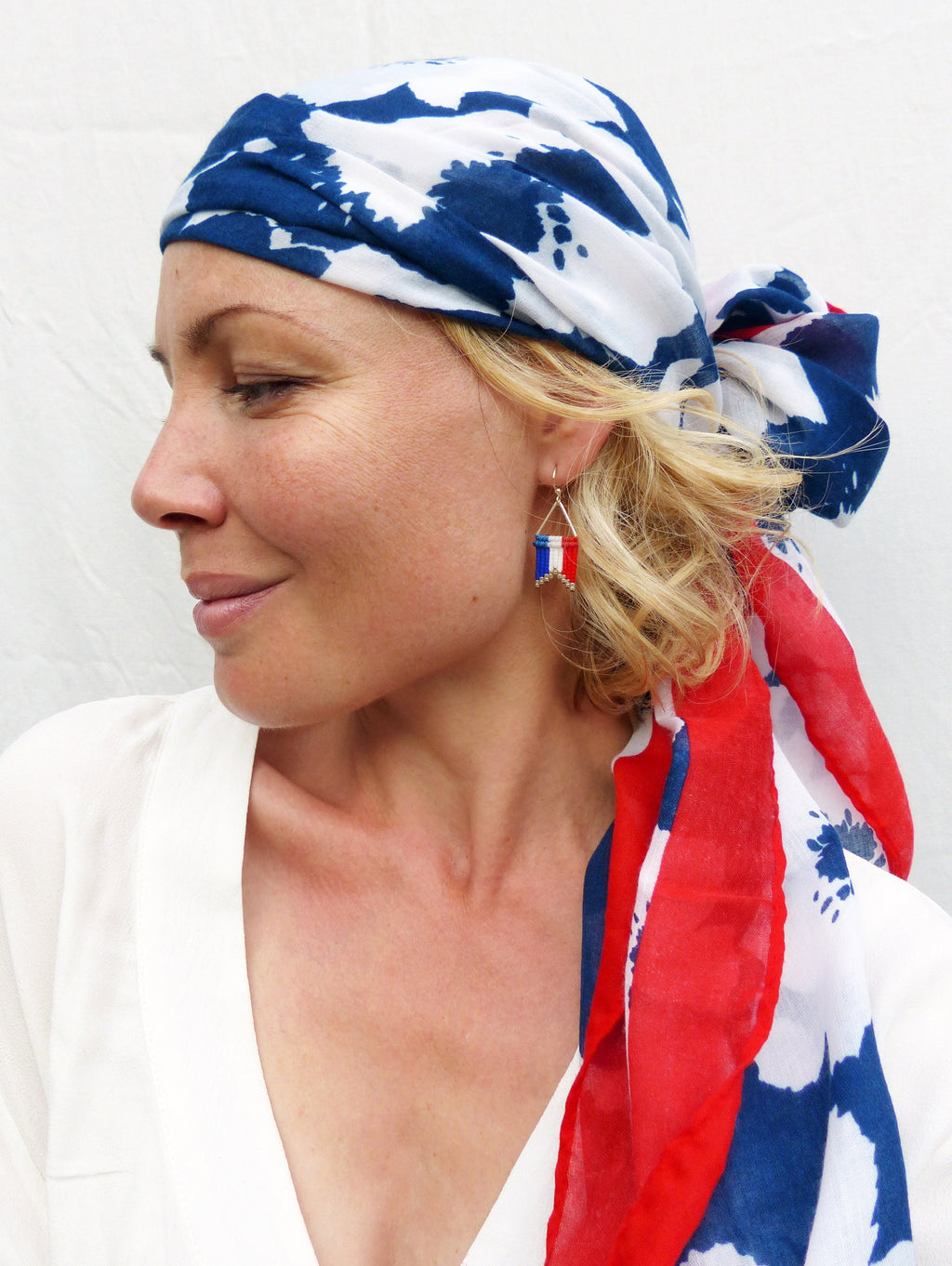 Peut inclure: Une femme portant un foulard à motifs blancs, bleus et rouges avec une boucle d'oreille argentée ornée d'un petit charme de drapeau français.
