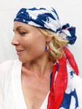 Peut inclure: Une femme portant un foulard à motifs blancs, bleus et rouges avec une boucle d'oreille argentée ornée d'un petit charme de drapeau français.