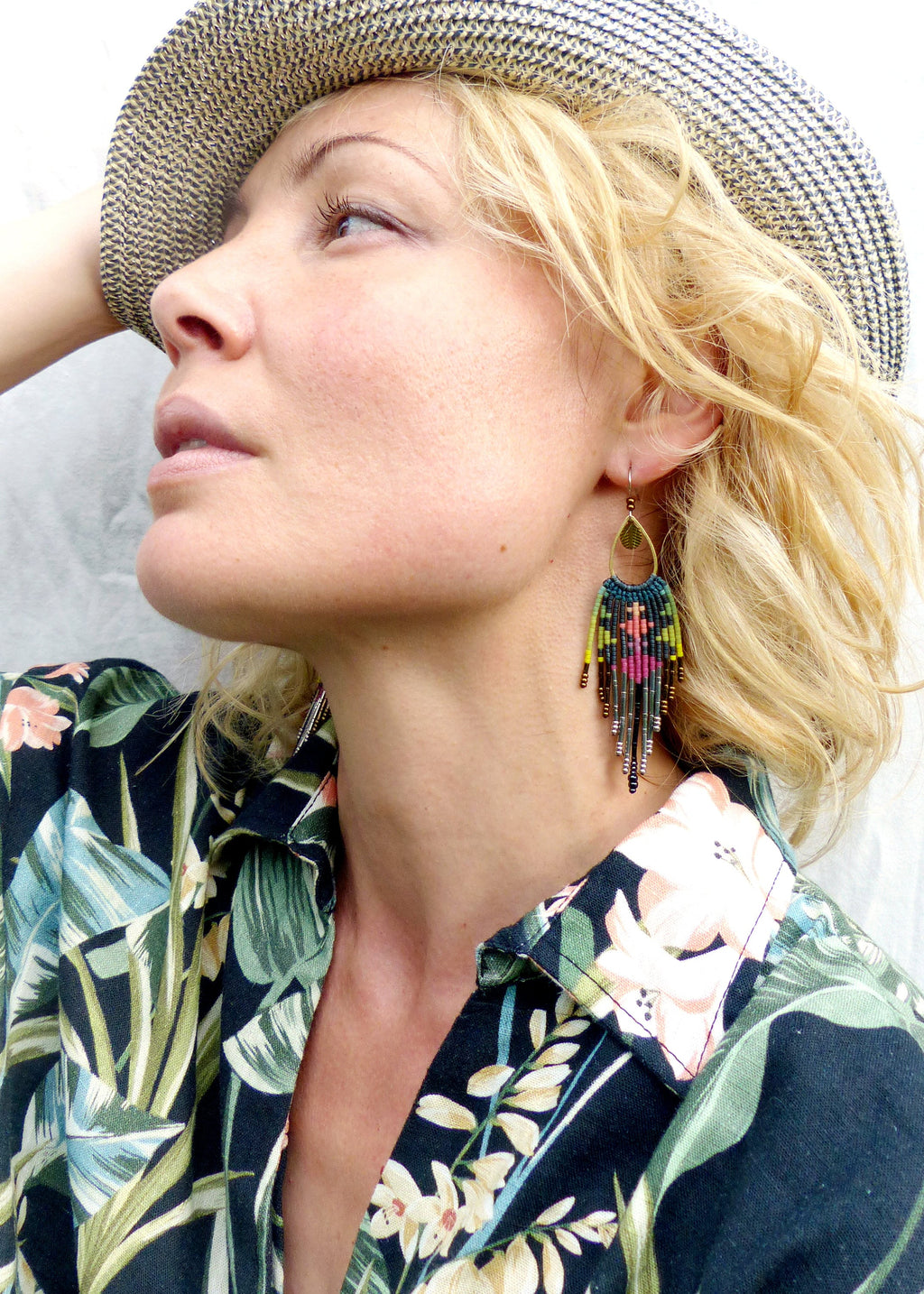 Peut inclure: Une femme portant un chapeau de paille et une chemise à imprimé floral avec de longues boucles d'oreilles en perles. Les boucles d'oreilles sont vertes, jaunes, roses et brunes.
