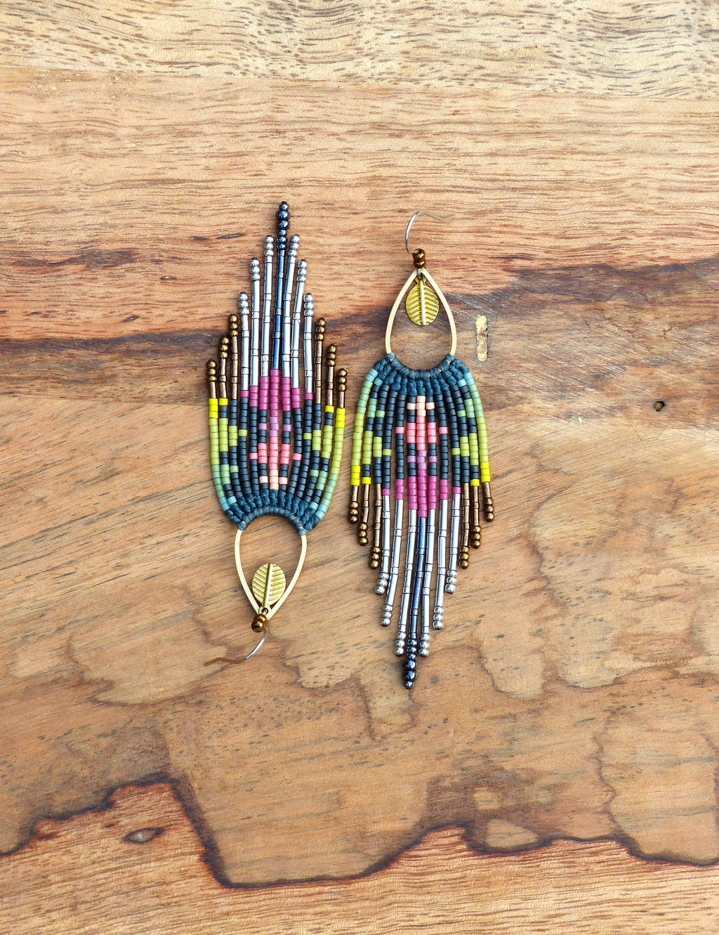 Peut inclure: Une paire de longues boucles d'oreilles en perles colorées avec un charme en forme de feuille au bas. Les boucles d'oreilles sont faites avec une variété de perles, y compris l'argent, l'or et la turquoise.