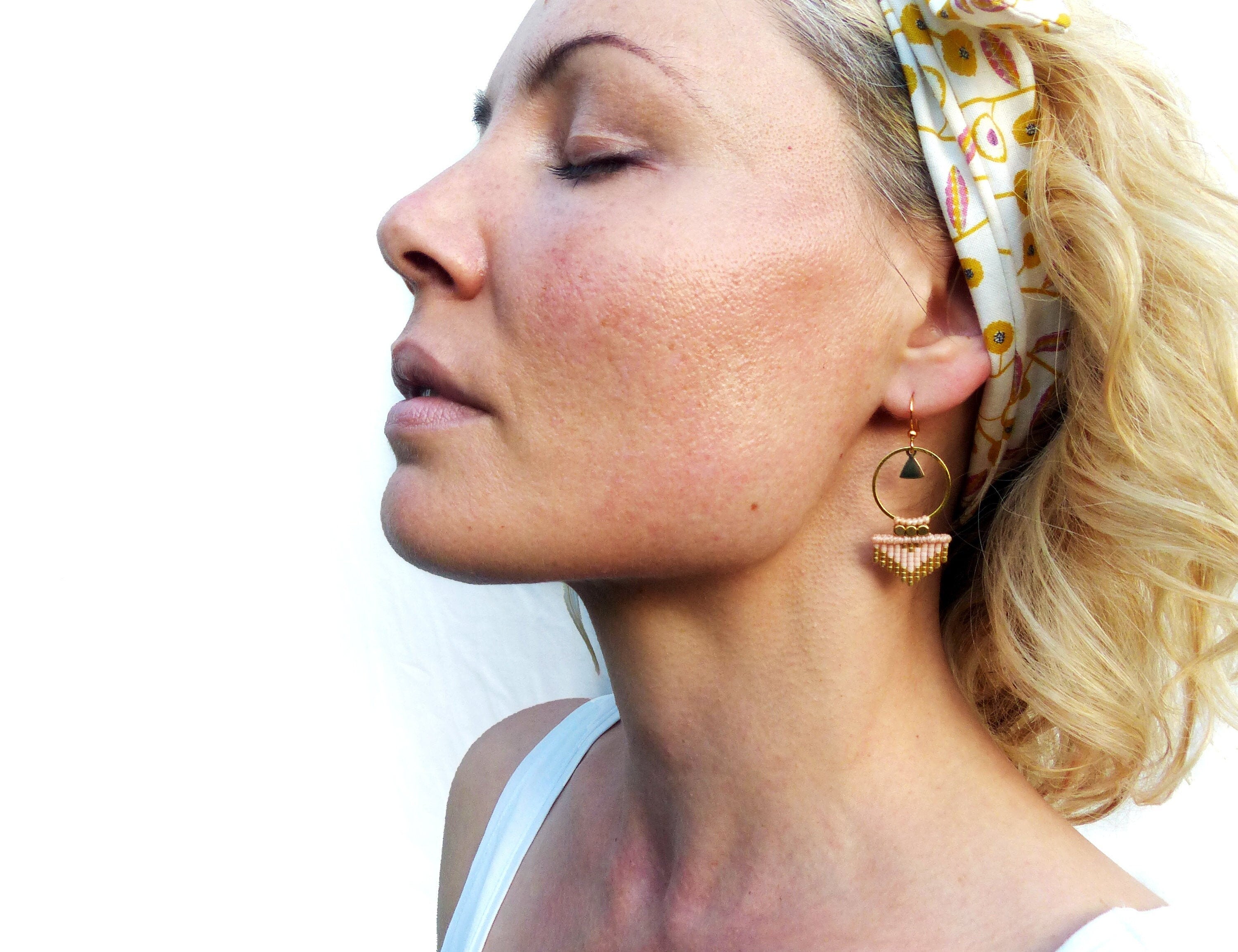 Peut inclure: Une paire de boucles d'oreilles en perles dorées et roses avec un design géométrique. Les boucles d'oreilles présentent un petit charme triangulaire et un anneau avec une frange de perles.
