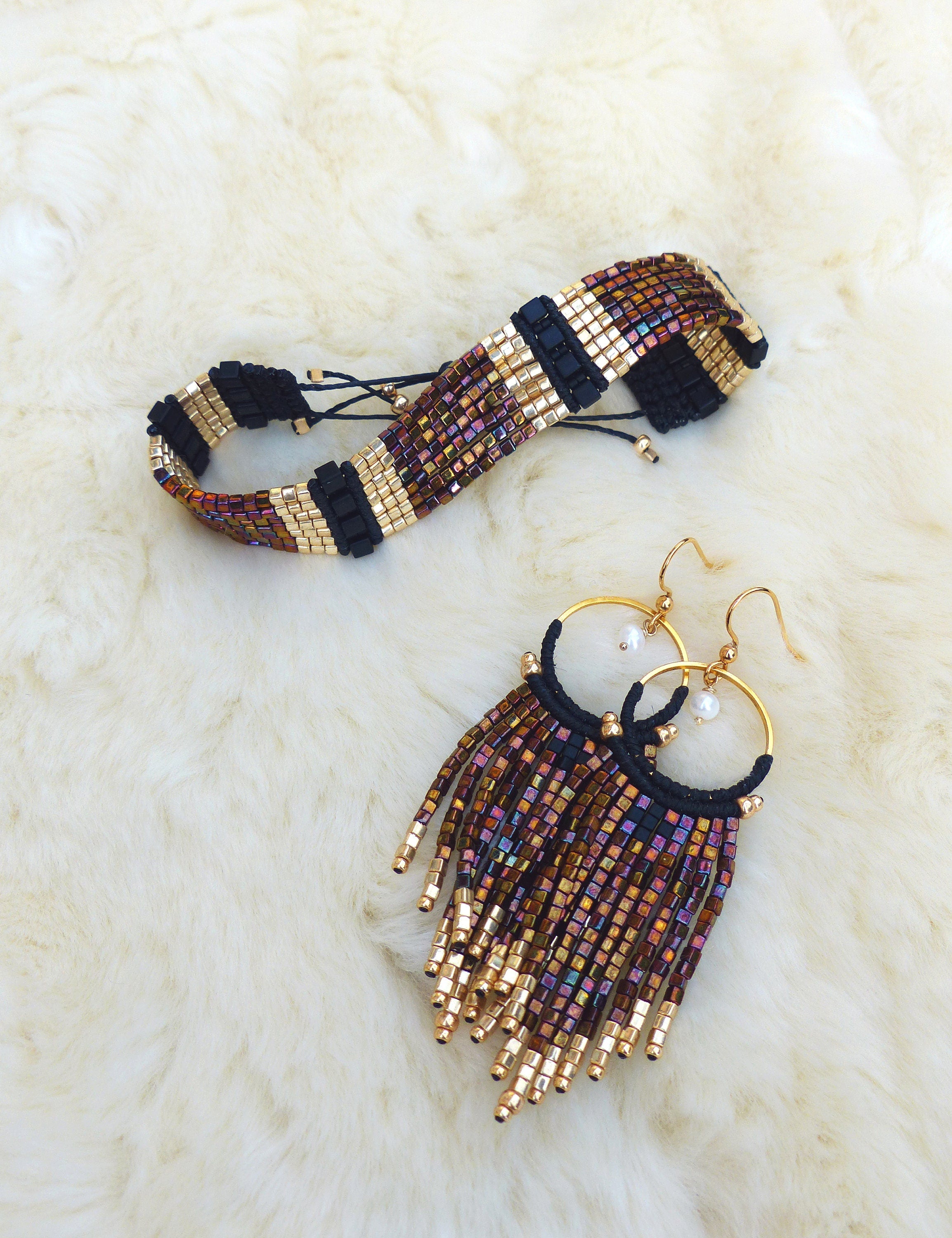Peut inclure: Un ensemble de bijoux en perles comprenant un bracelet noir et or avec un design en frange et des boucles d'oreilles assorties avec des anneaux dorés et un design en frange.