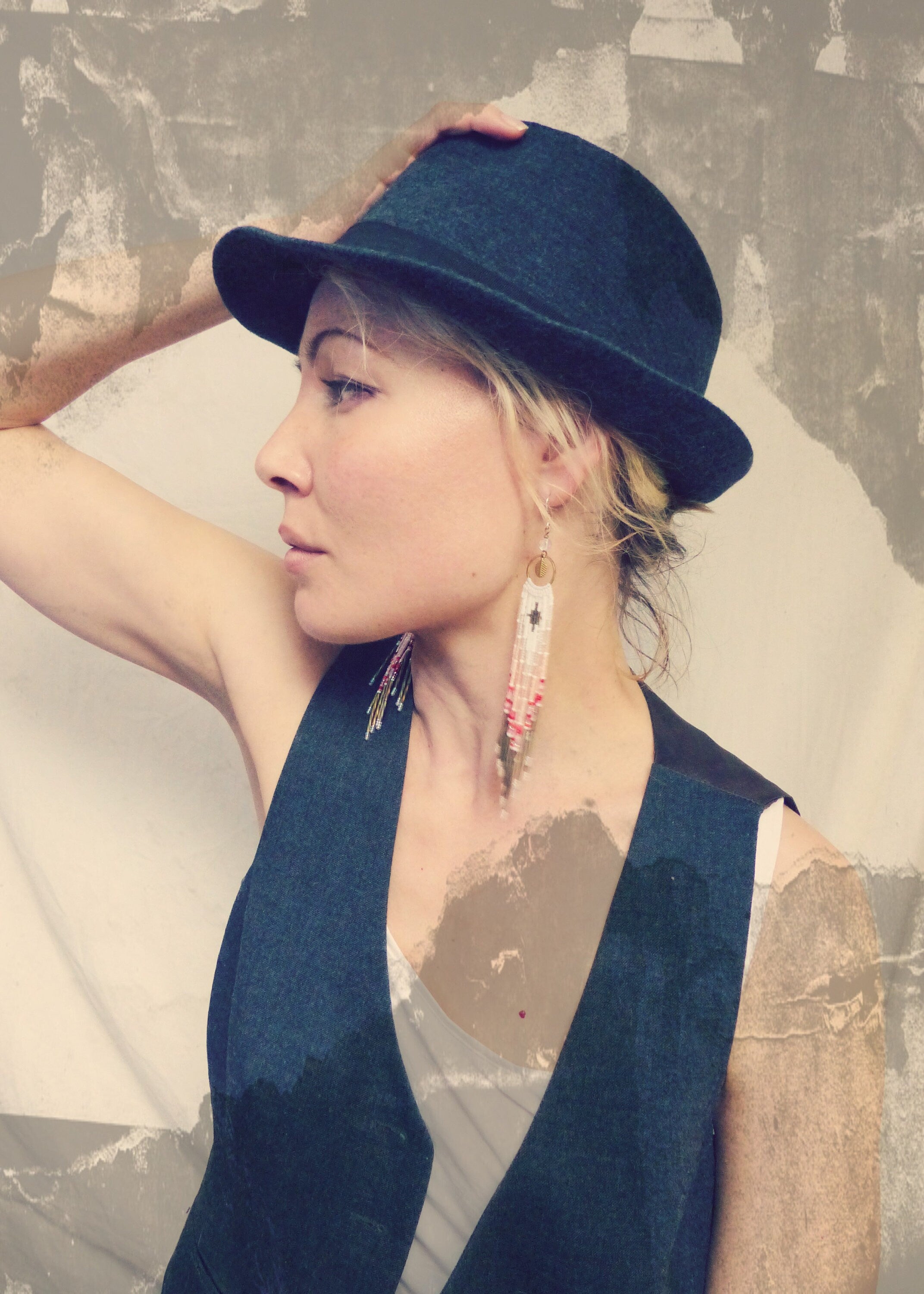 Peut inclure: Une femme portant un gilet bleu foncé et un fedora bleu foncé avec une boucle d'oreille en perles blanches et rouges. 