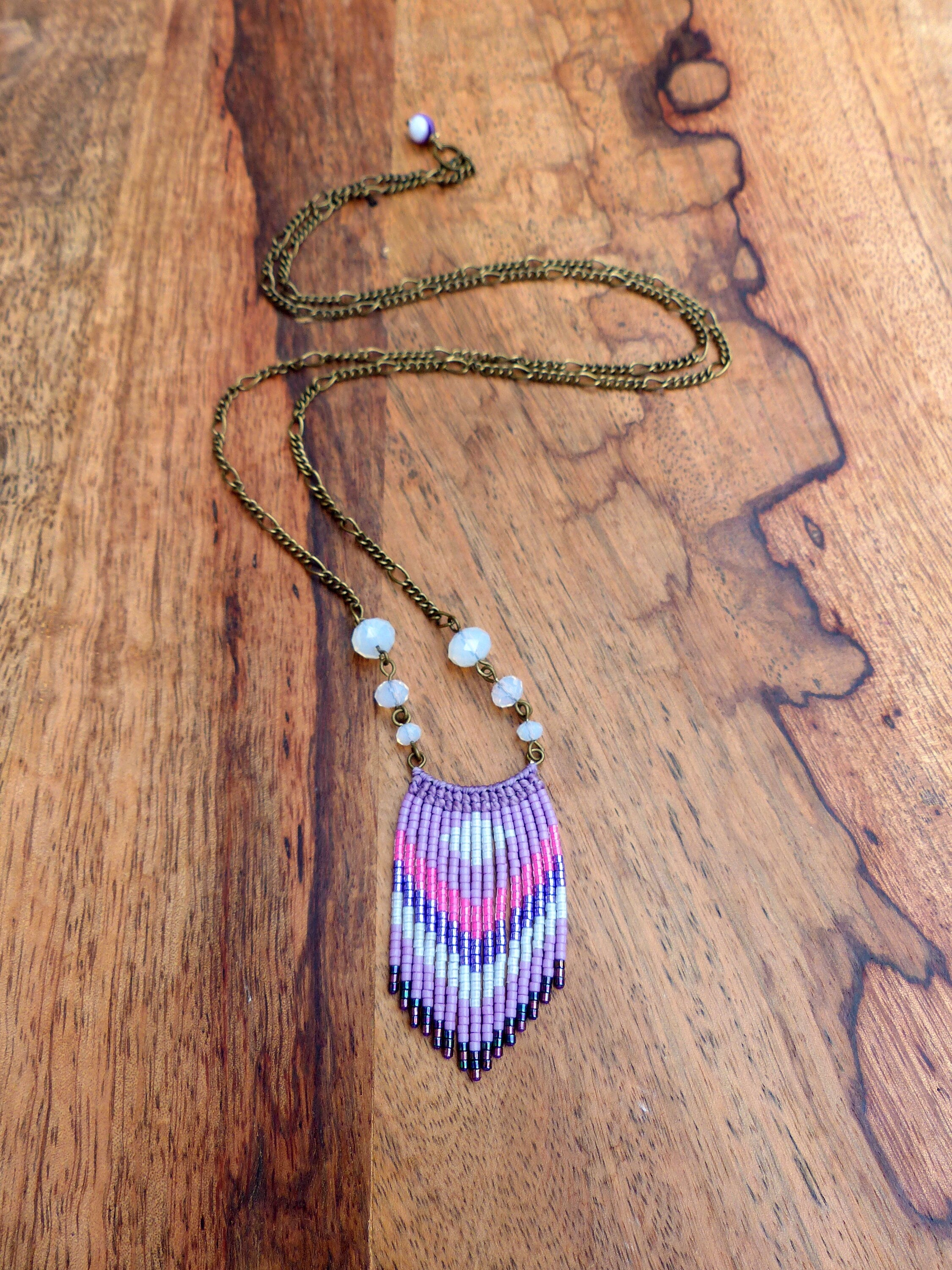 Peut inclure: Un collier de perles violettes, roses et blanches avec un pendentif en franges. Le collier est fait de petites perles de rocaille et a une chaîne en laiton.