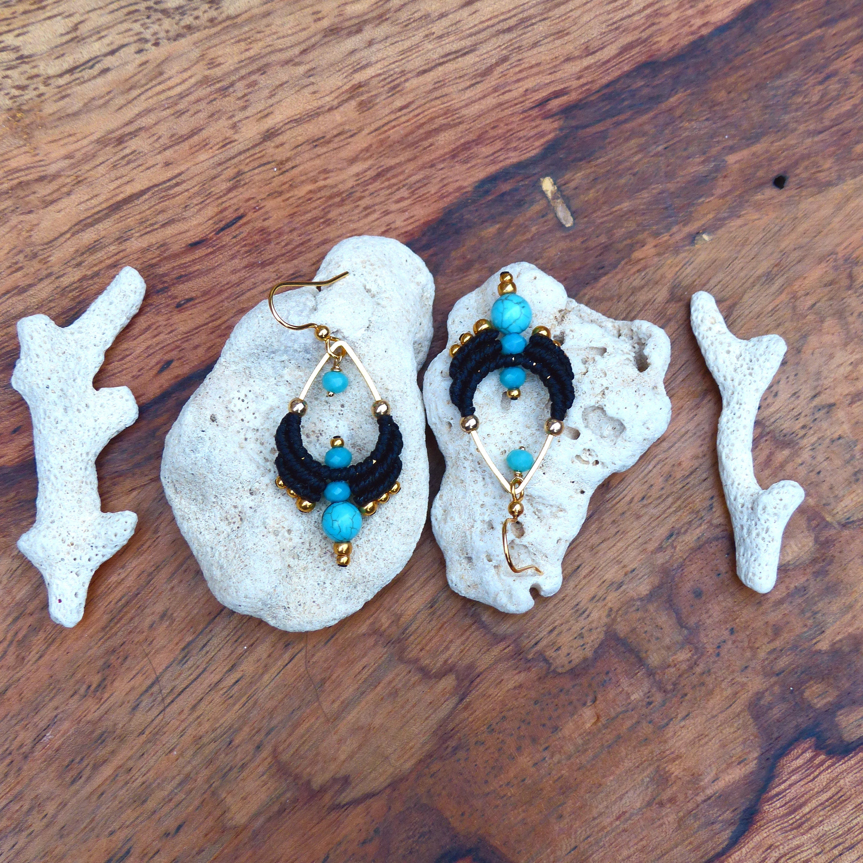 Peut inclure: Une paire de boucles d'oreilles pendantes en macramé noir et perles turquoise. Les boucles d'oreilles sont suspendues à des créoles dorées.