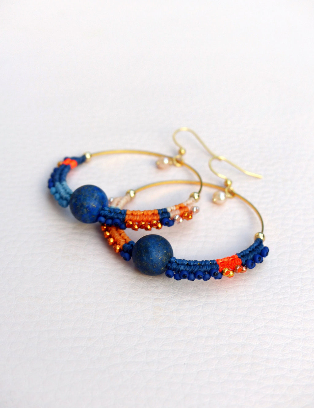 Peut inclure: Boucles d'oreilles créoles dorées avec des perles bleues et orange et un accent de pierre bleu foncé.